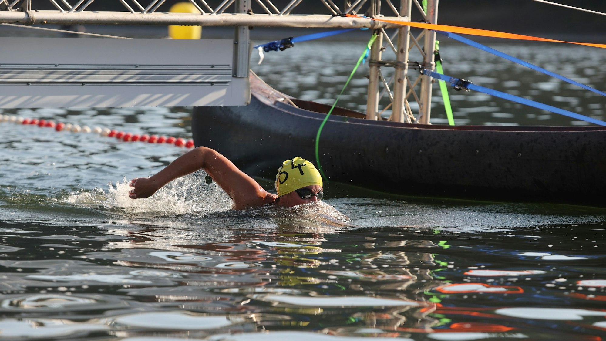 Zu sehen ist ein Frau mit gelber Badekappe, die in der Aggertalspere schwimmt.