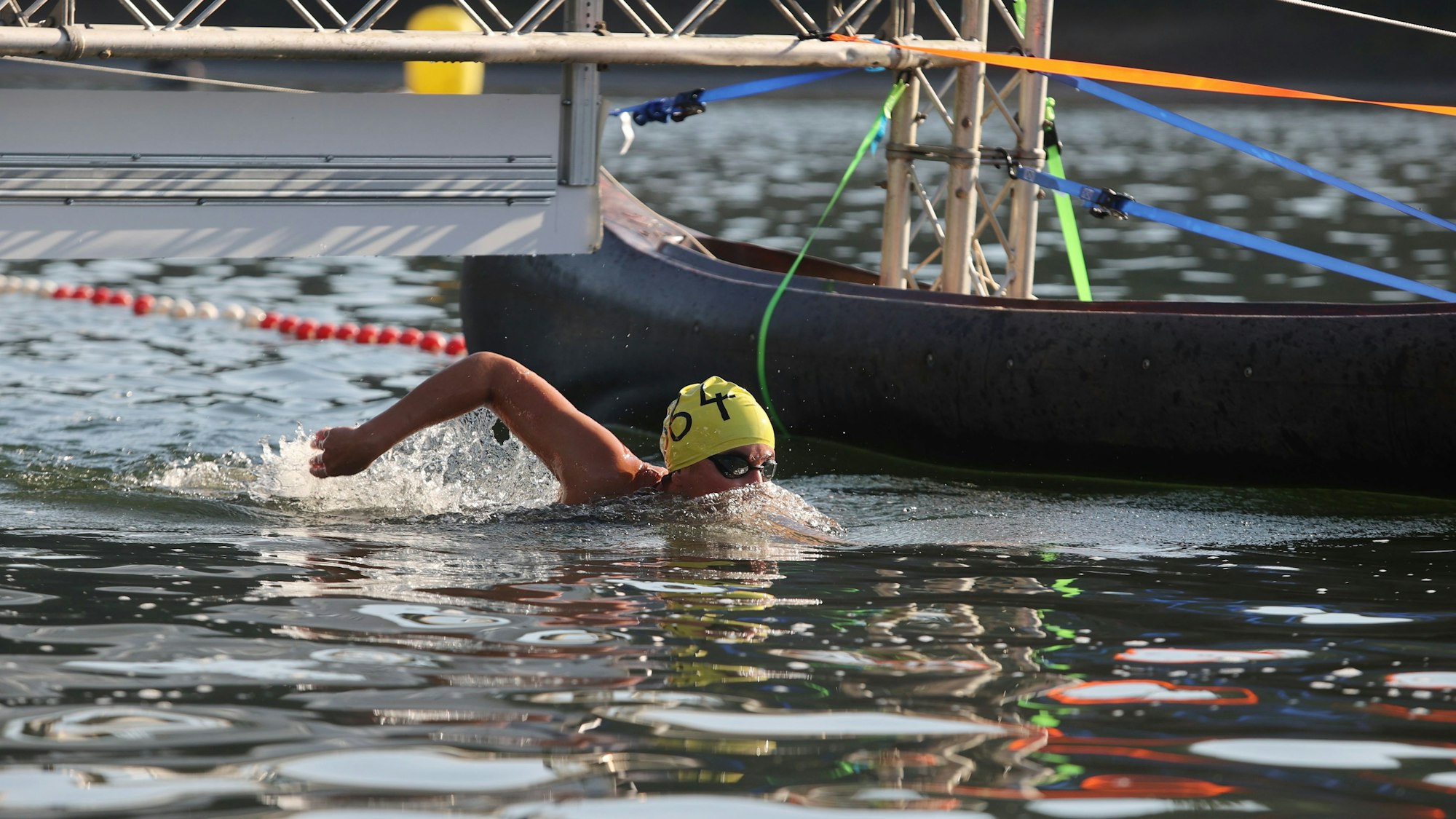 Zu sehen ist ein Frau mit gelber Badekappe, die in der Aggertalspere schwimmt.