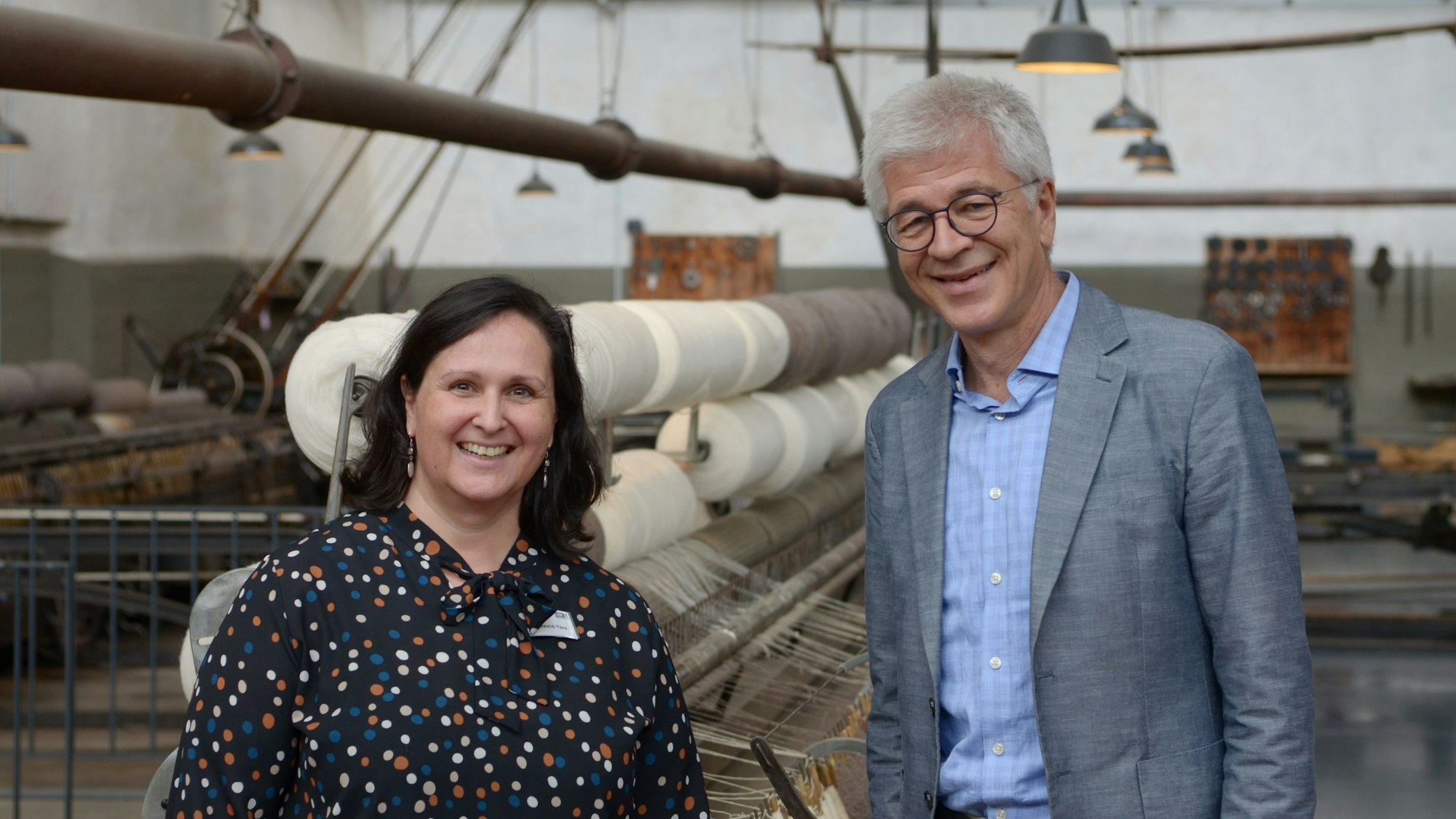 Eine Frau und ein Mann stehen nebeneinander und lächeln in die Kamera.