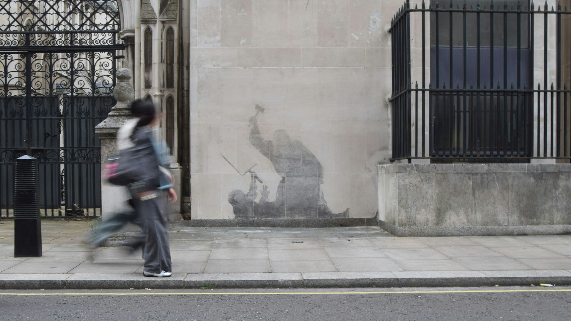 Menschen gehen an dem neuesten Kunstwerk des britischen Künstlers Banksy an den Royal Courts of Justice vorbei. Das Werk wurde teilweise schon wieder entfernt.