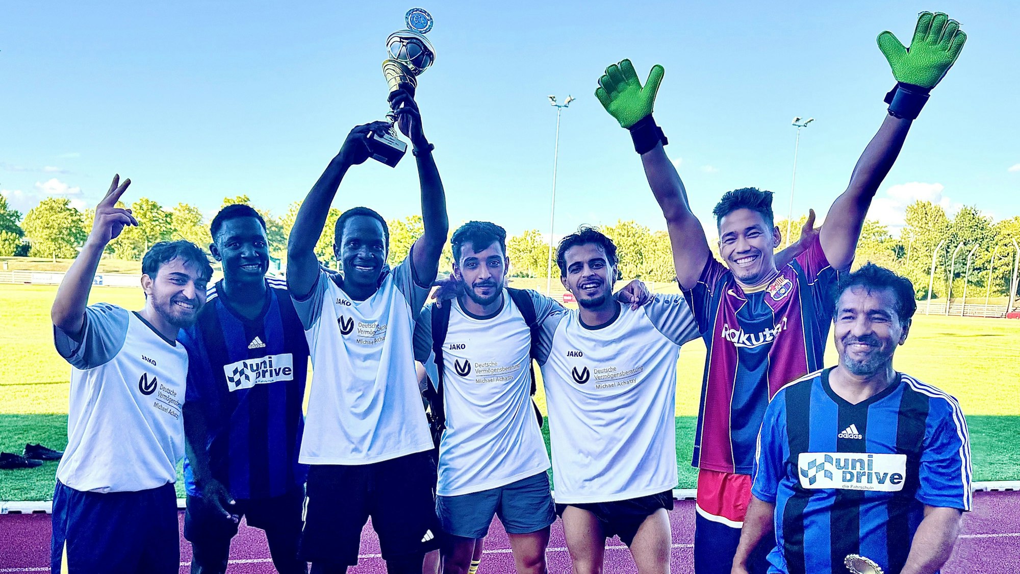 Die Mitglieder der siegreichen Mannschaft stehen jubelnd nebeneinander, einer hält einen Pokal in die Höhe.