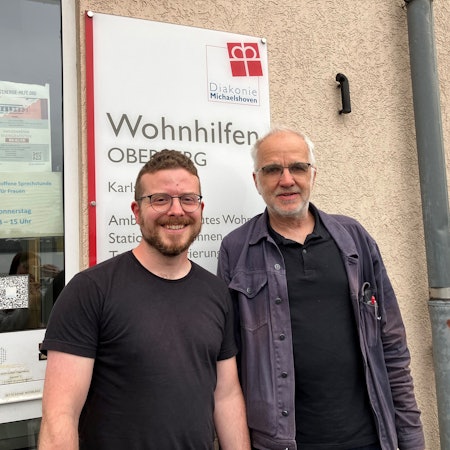 Morten Kochhäuser und Wilfried Fenner stehen gemeinsam vor dem Gebäude in Gummersbach, in dem Büros der Wohnhilfen Oberberg Mitte untergebracht sind.
