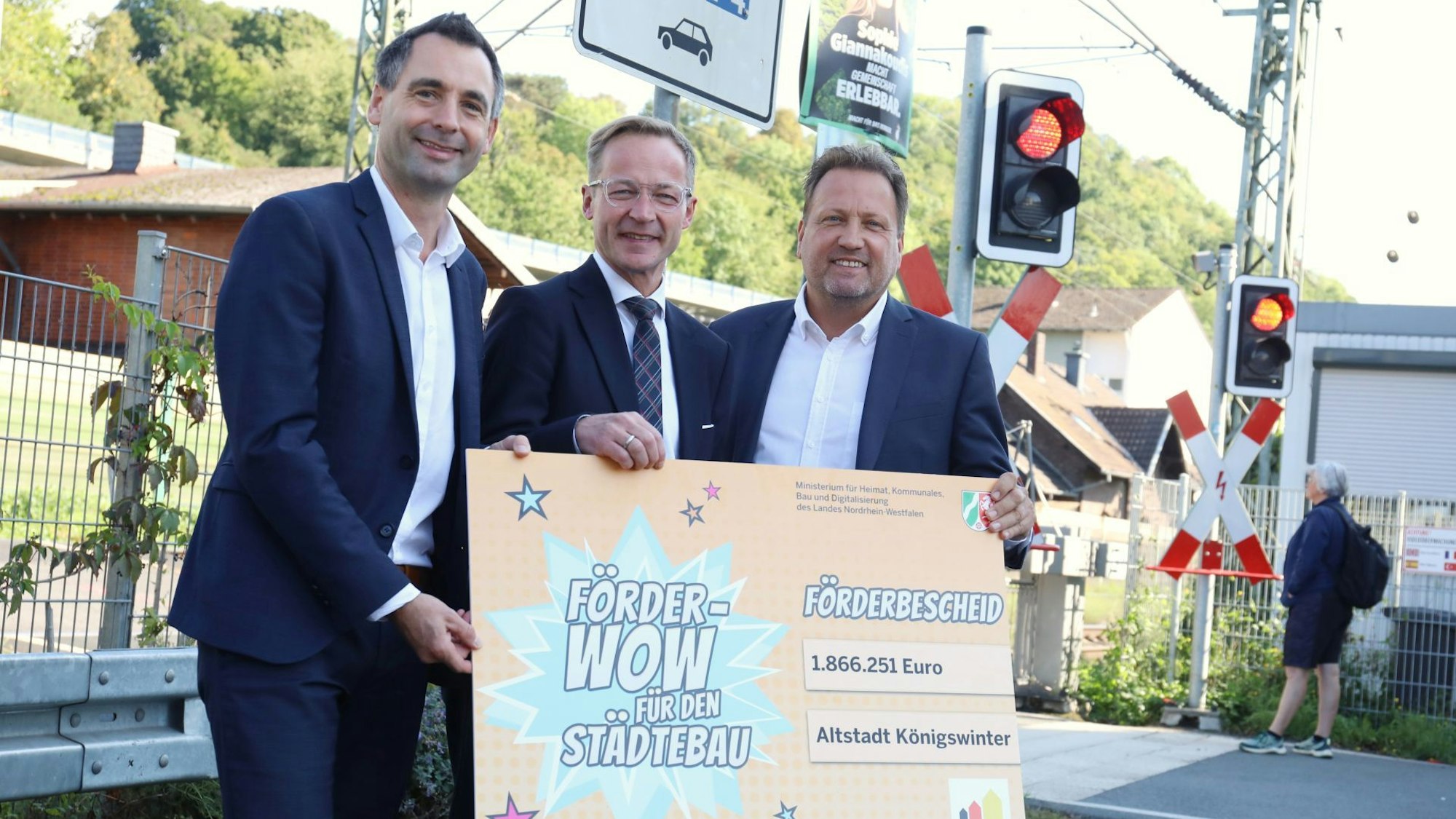 Drei Männer halten ein großes Schild mit der Aufschrift „Förder-Wow ... für den Städtebau“.