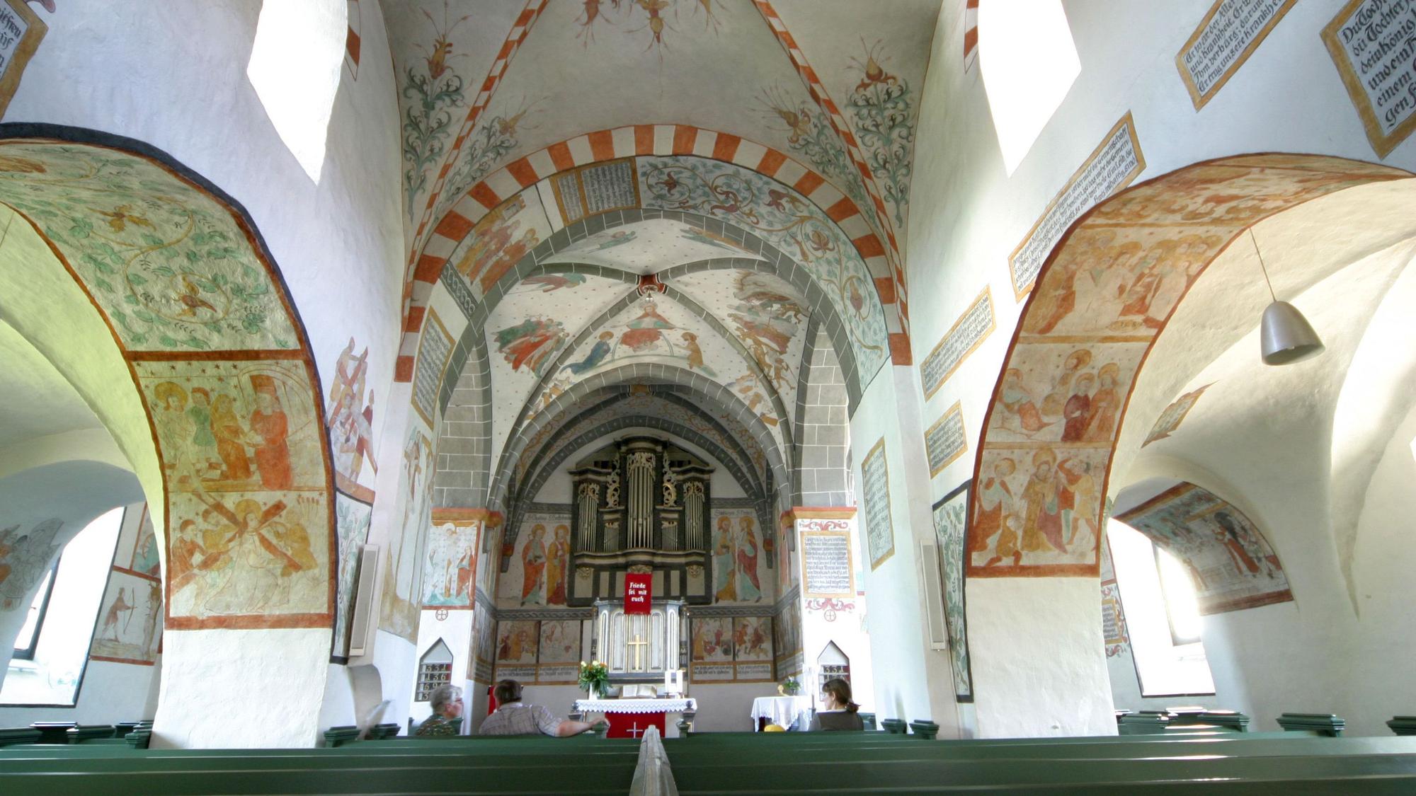Blick in eine Kirche mit bunten Fresken an den Wänden.