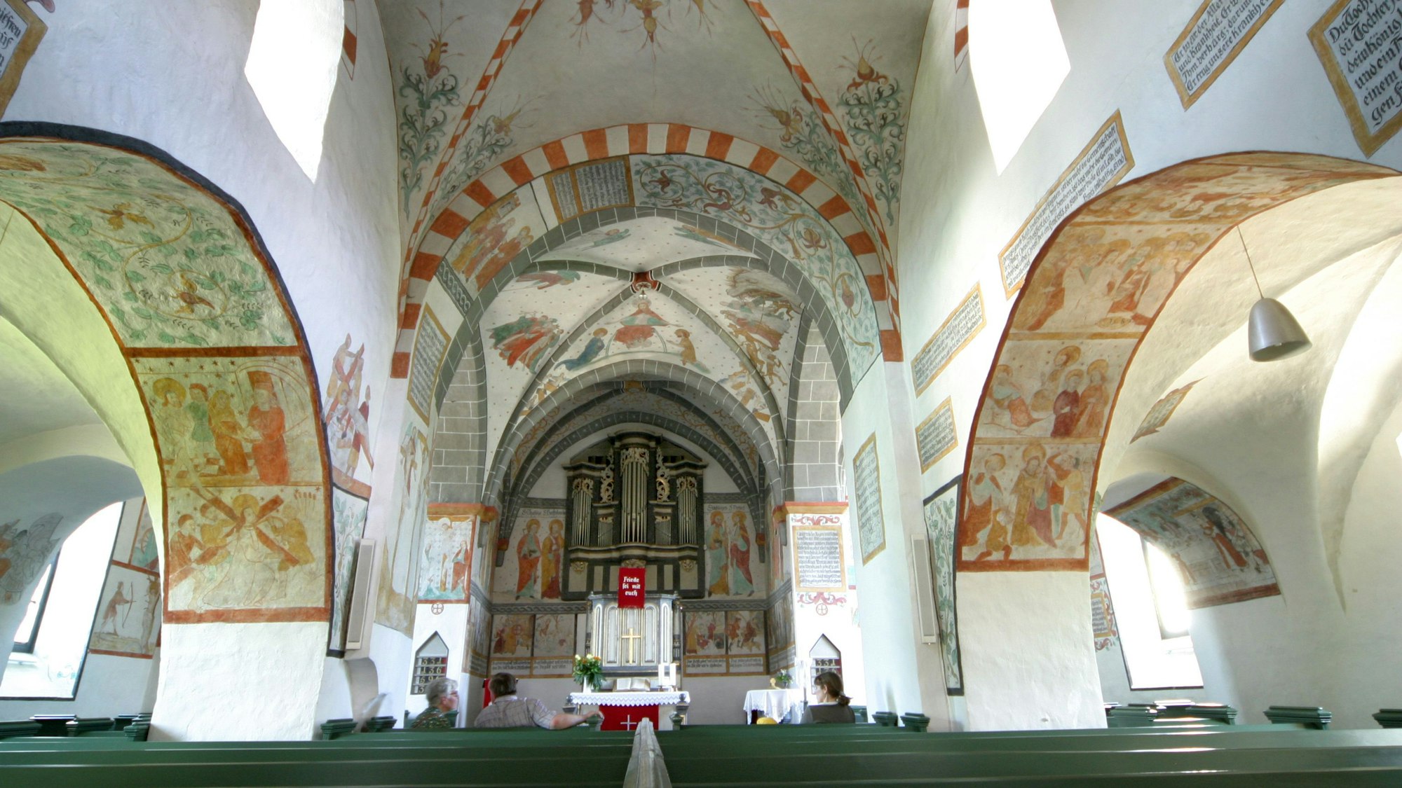 Blick in eine Kirche mit bunten Fresken an den Wänden.