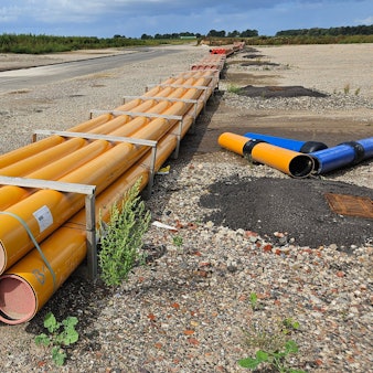 Zu sehen sind Rohrleitungen neben einer Baustraße.