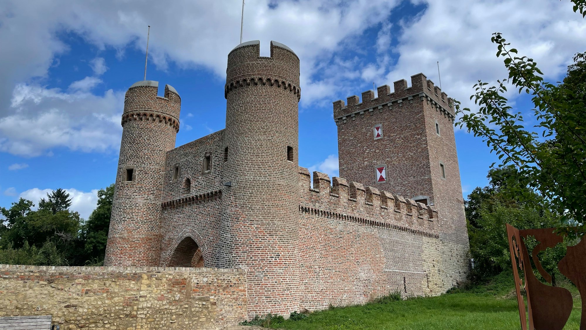 Ein Blick auf das von Bäumen gesäumte Weiertor mit Hauptturm und zwei Rundtürmen.