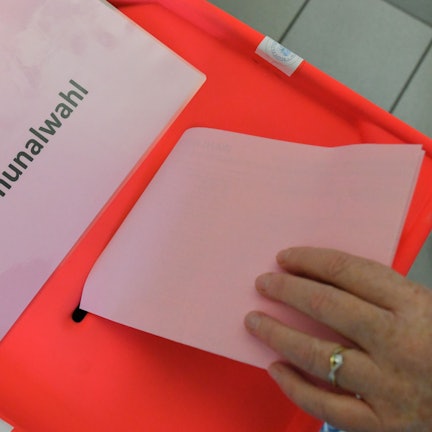 Eine Wählerin steckt ihren Stimmzettel zur Kommunalwahl in die Wahlurne.
