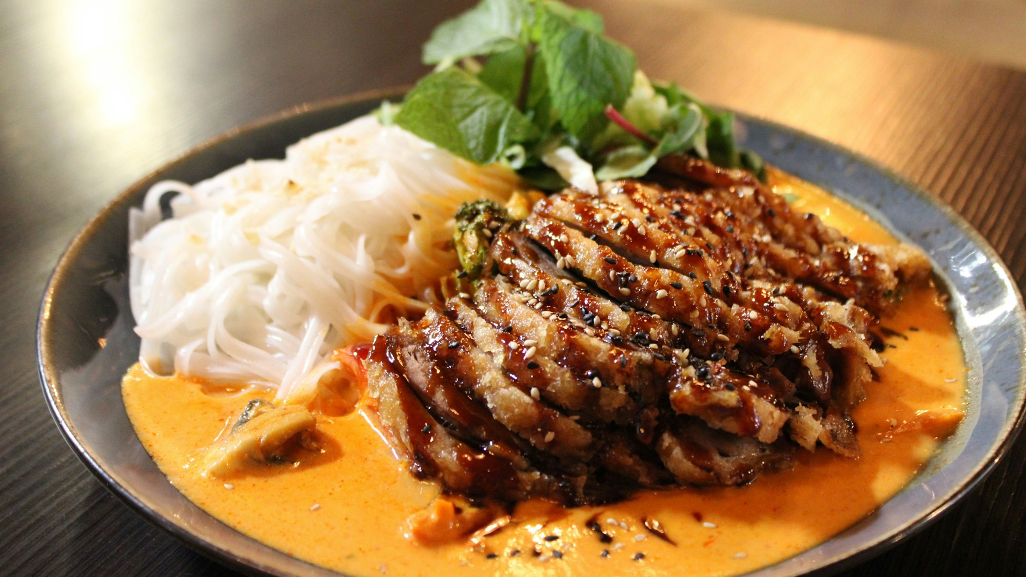 Gastronomische Einflüsse aus verschiedenen asiatischen Ländern: Curry mit knuspriger Ente, saisonalem Gemüse und Reisbandnudeln.