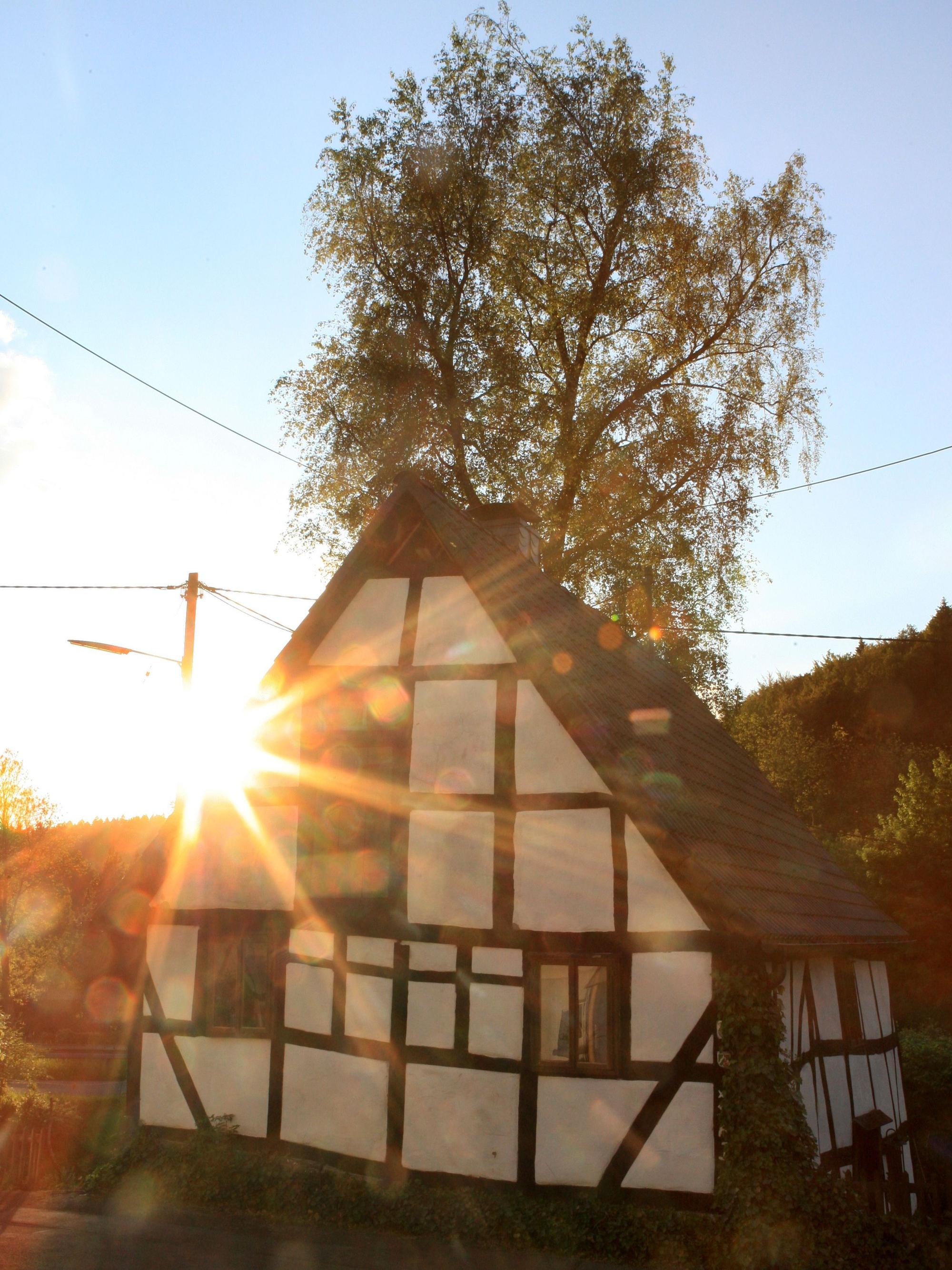 Ein Fachwerkhaus in Niederrengse ist im Gegenlicht der untergehenden Sonne zu sehen..