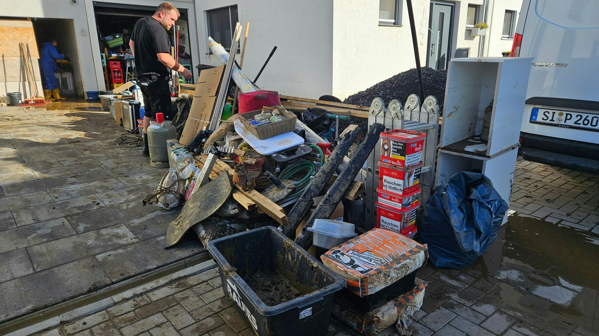 In einer Auffahrt vor einer Garage steht verschlammter Sperrmüll.