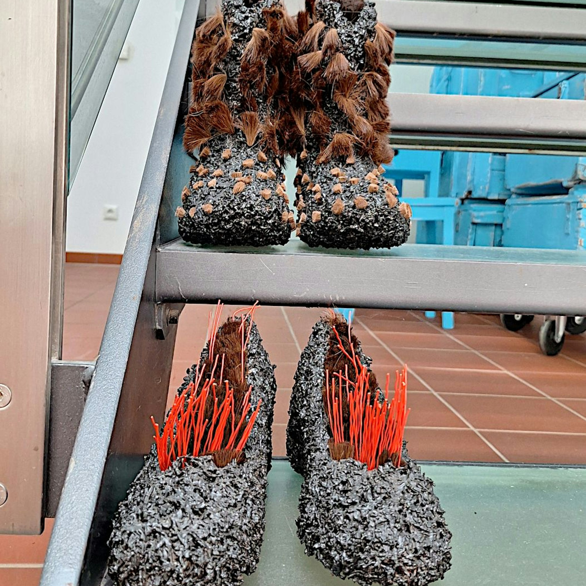 Mit Teeblättern und Ponyhaar beklebte Damenschuhe stehen auf einer Treppe.