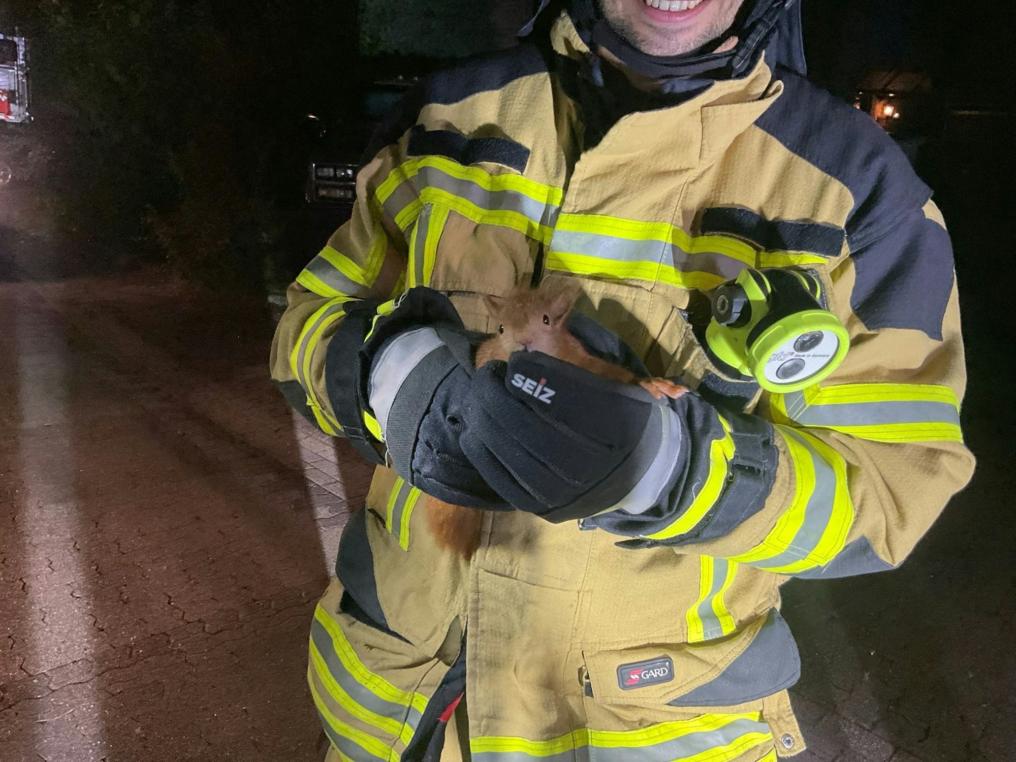 Ein Feuerwehrmann hält ein gerettetes Eichhörnchen in den Händen. Das Tier war in einem Dach steckengeblieben.