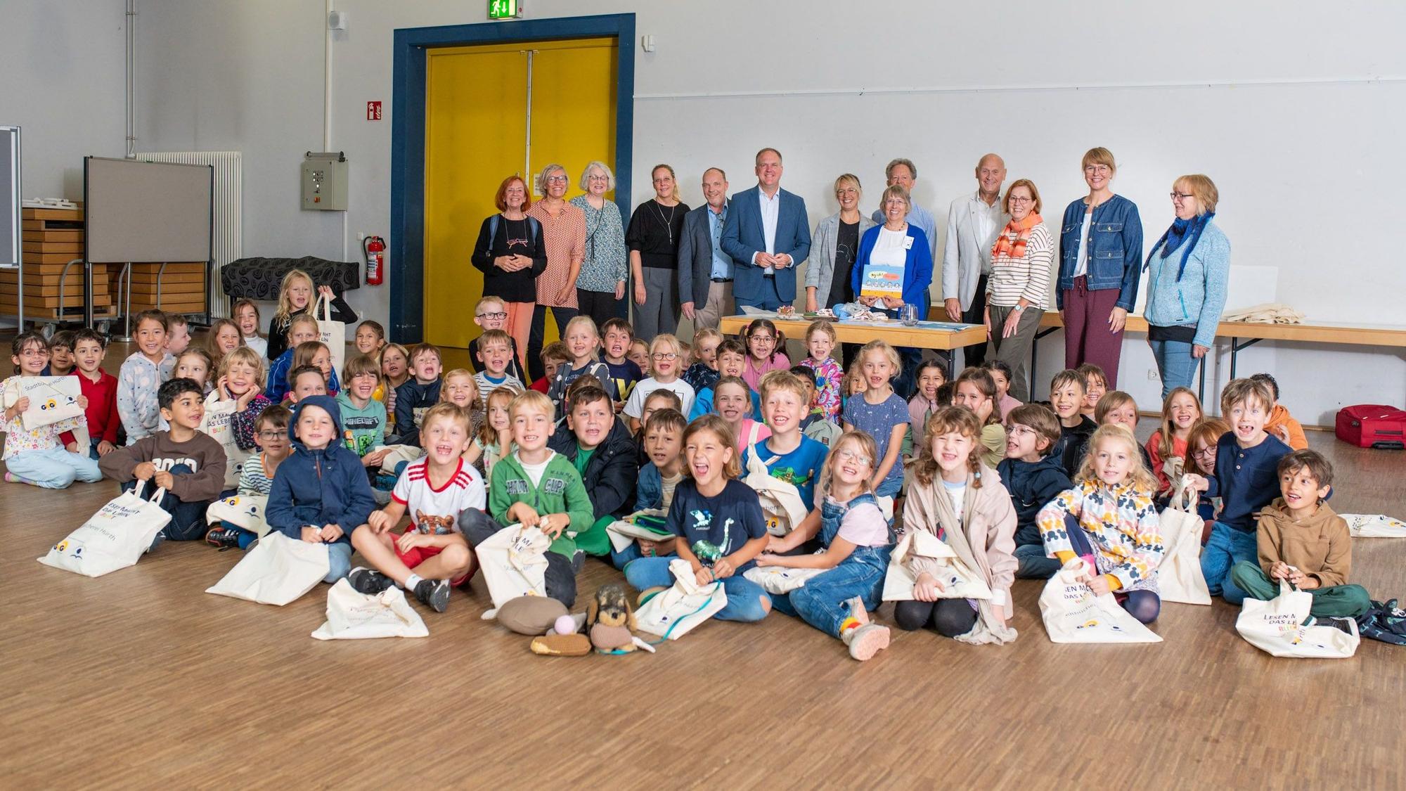 Das Foto zeigt die Schulkinder mit ihren Lesetaschen, dahinter die Vertreter der Stadt, der Leserfreunde und der Sponsoren.