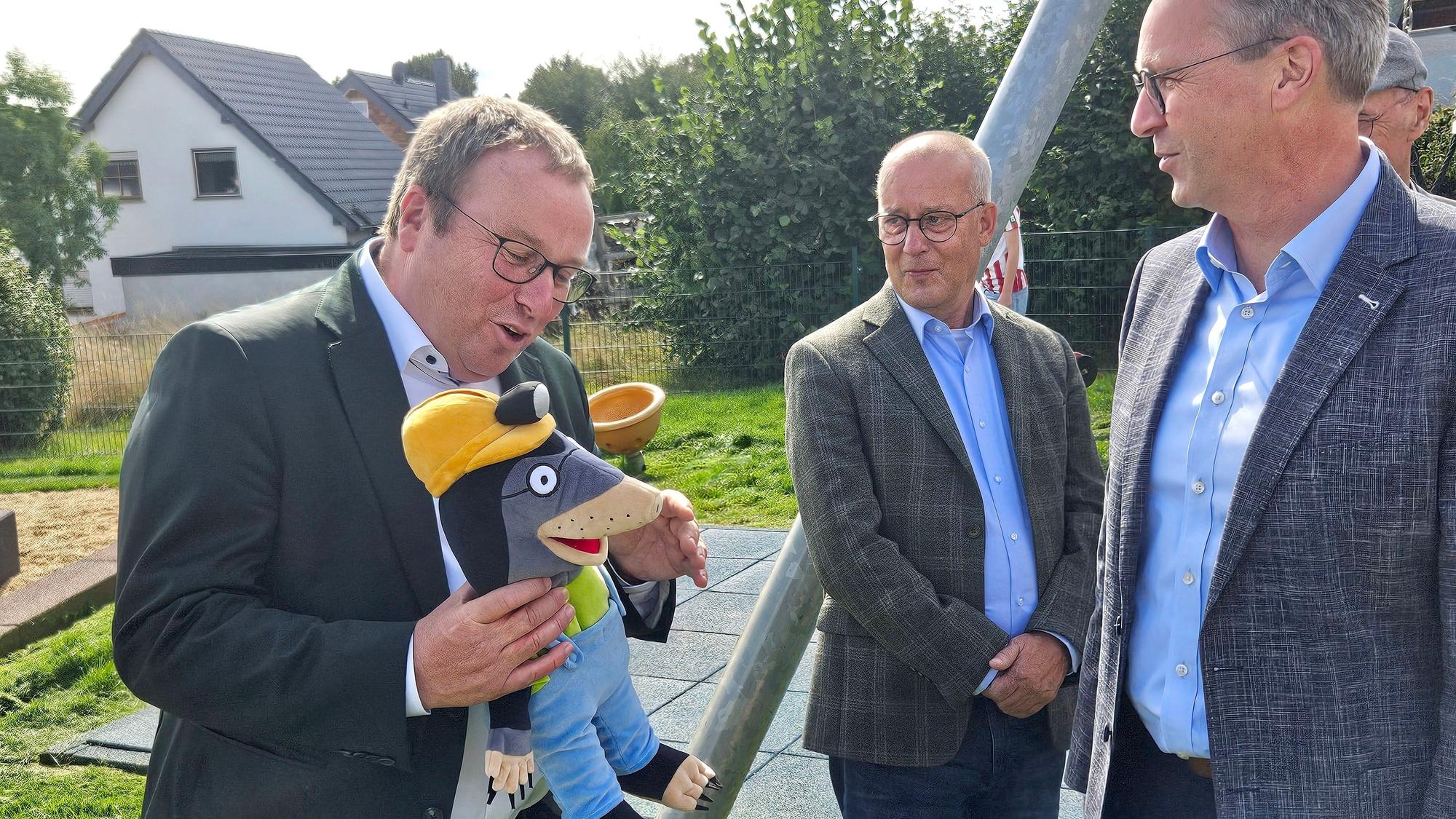 Umweltminister Oliver Krischer hält eine Plumbi-Figur, einen Stoff-Maulwurf, in den Händen und lacht.