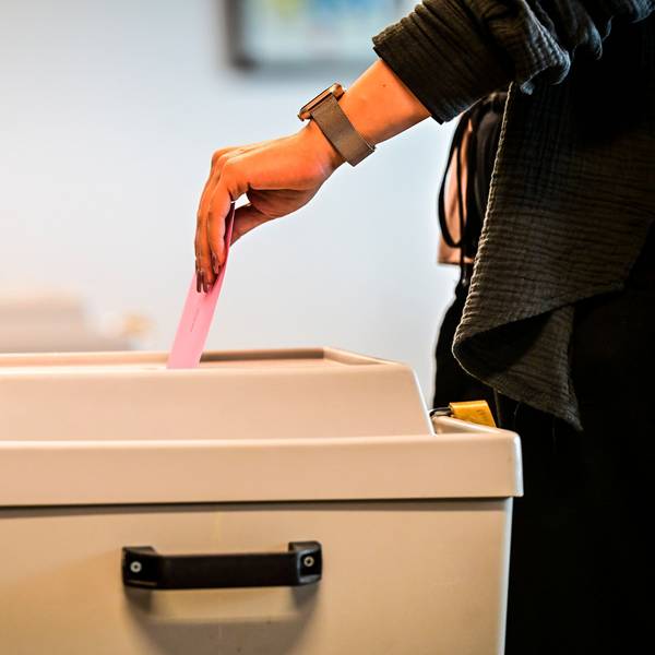 Ein Wähler wirft den Briefumschlag in die Wahlurne.