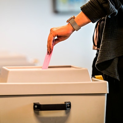 Ein Wähler wirft den Briefumschlag in die Wahlurne.