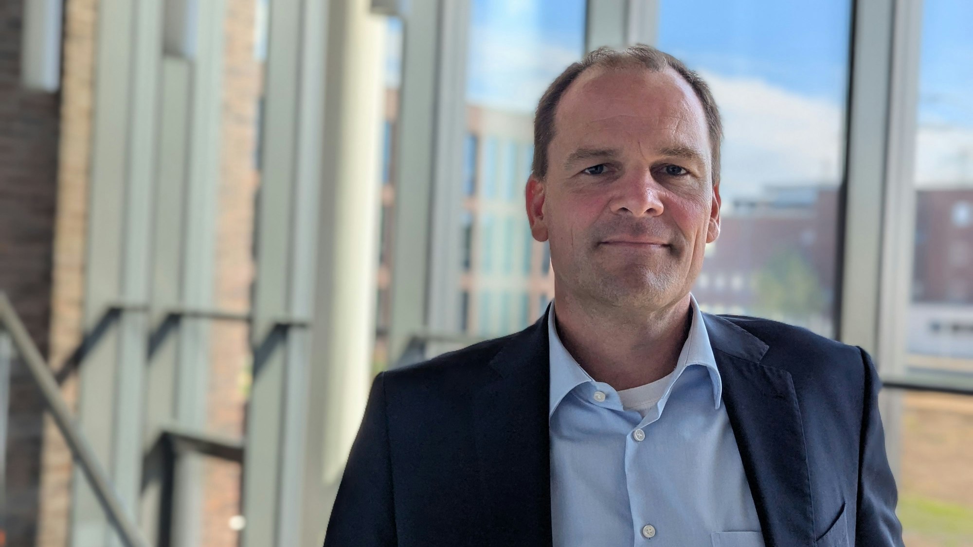 Das Foto zeigt den Amprion-Manager auf einer Treppe vor einer Glasfassade im Neubau auf dem Campus in Brauweiler