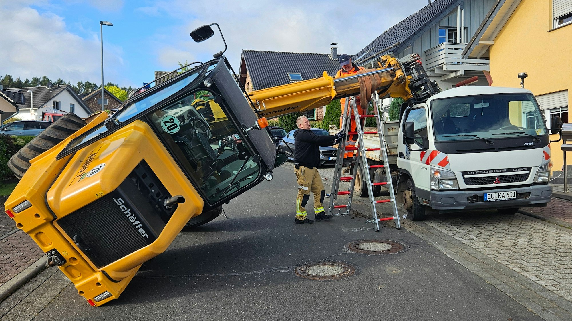 Der Hubarm eines umgekippter Radladers wird mit einer Leiter gestützt.