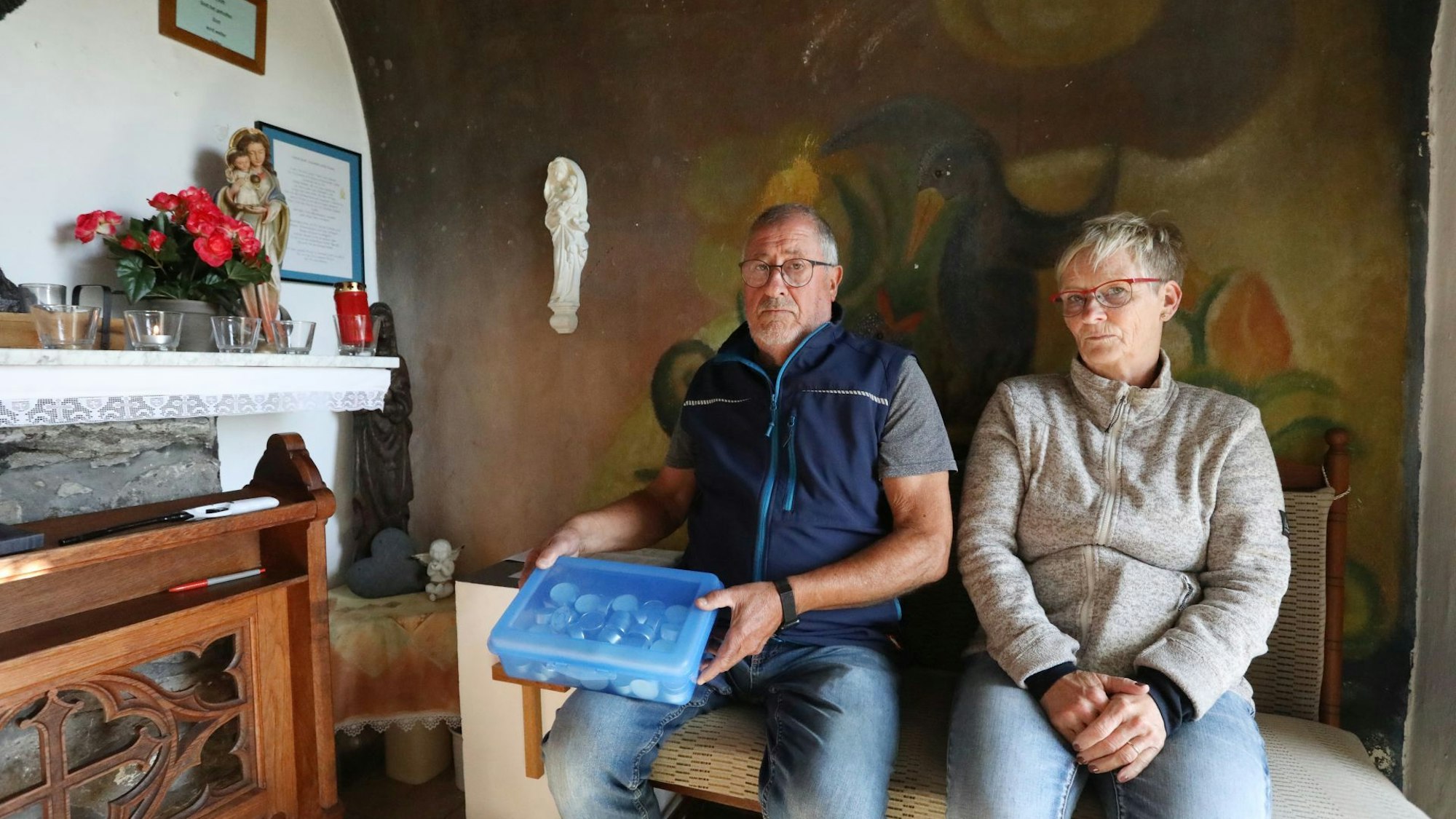 Ein Paar sitzt auf einer Bank, der Mann hält eine blaue Box in den Händen.