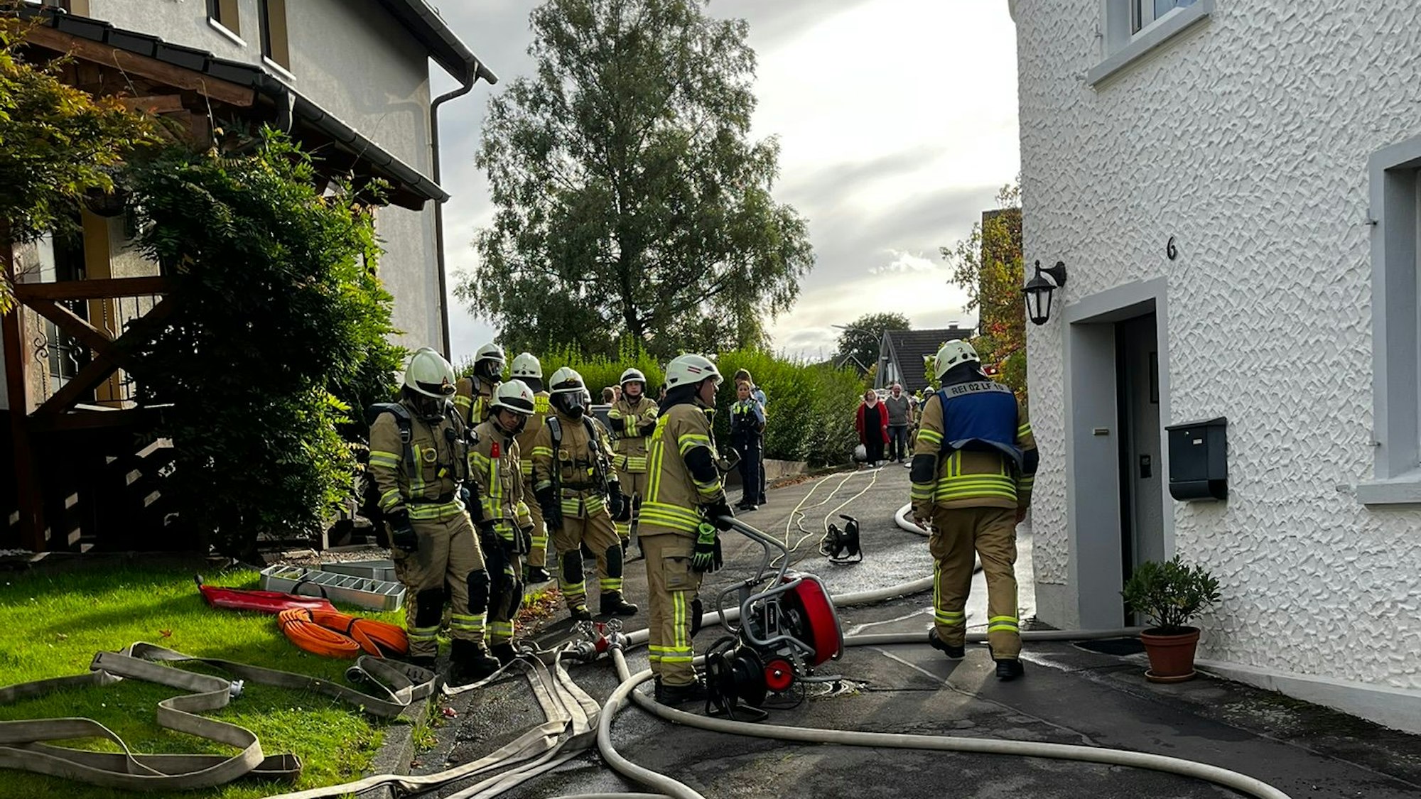 Mehrere Feuerwehrleute stehen vor einem Wohnhaus.