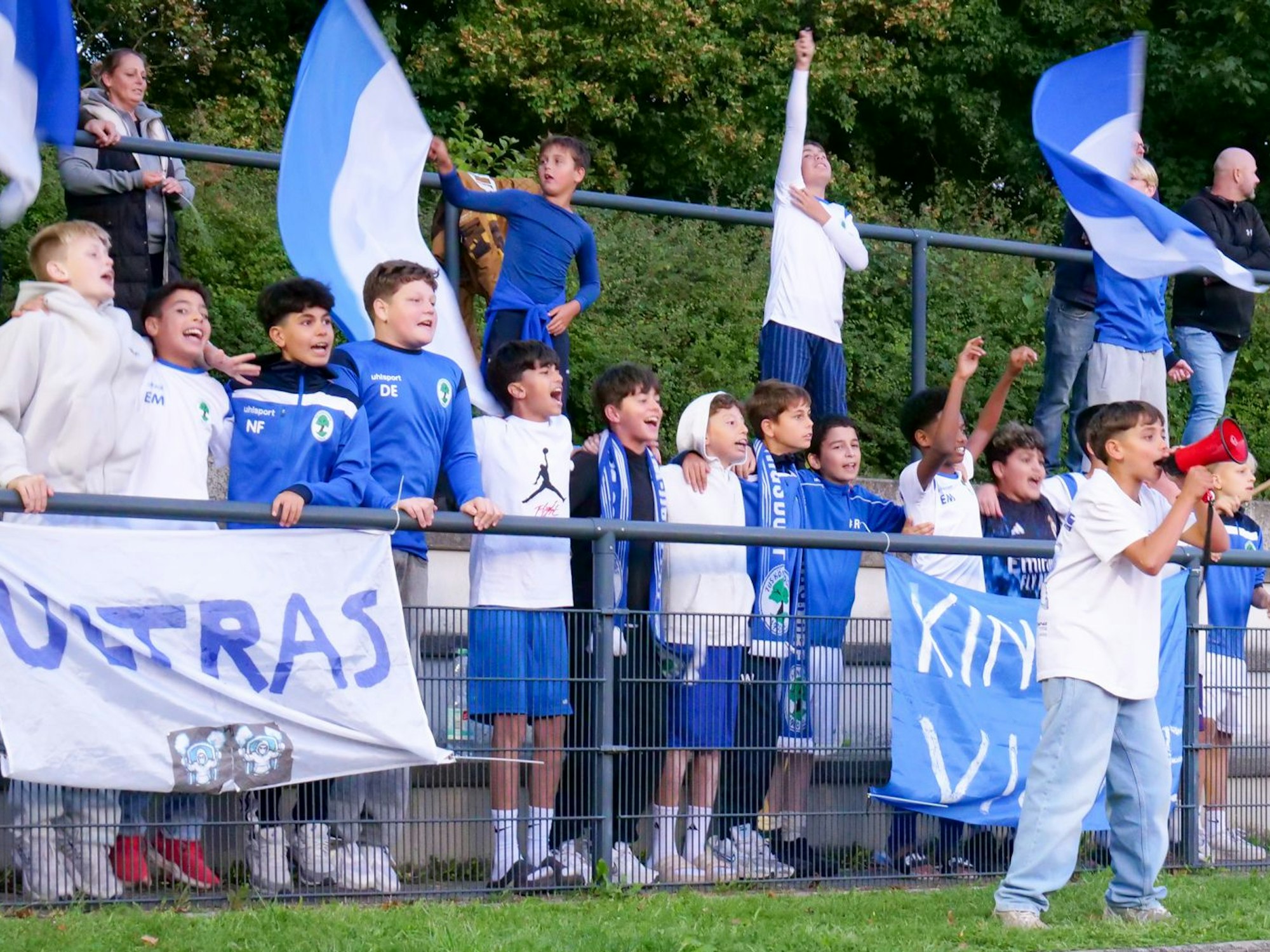Die Fans des Königsdorfer Auswärtsteams sind mit Megafon und vielen Fahnen ausgerüstet.