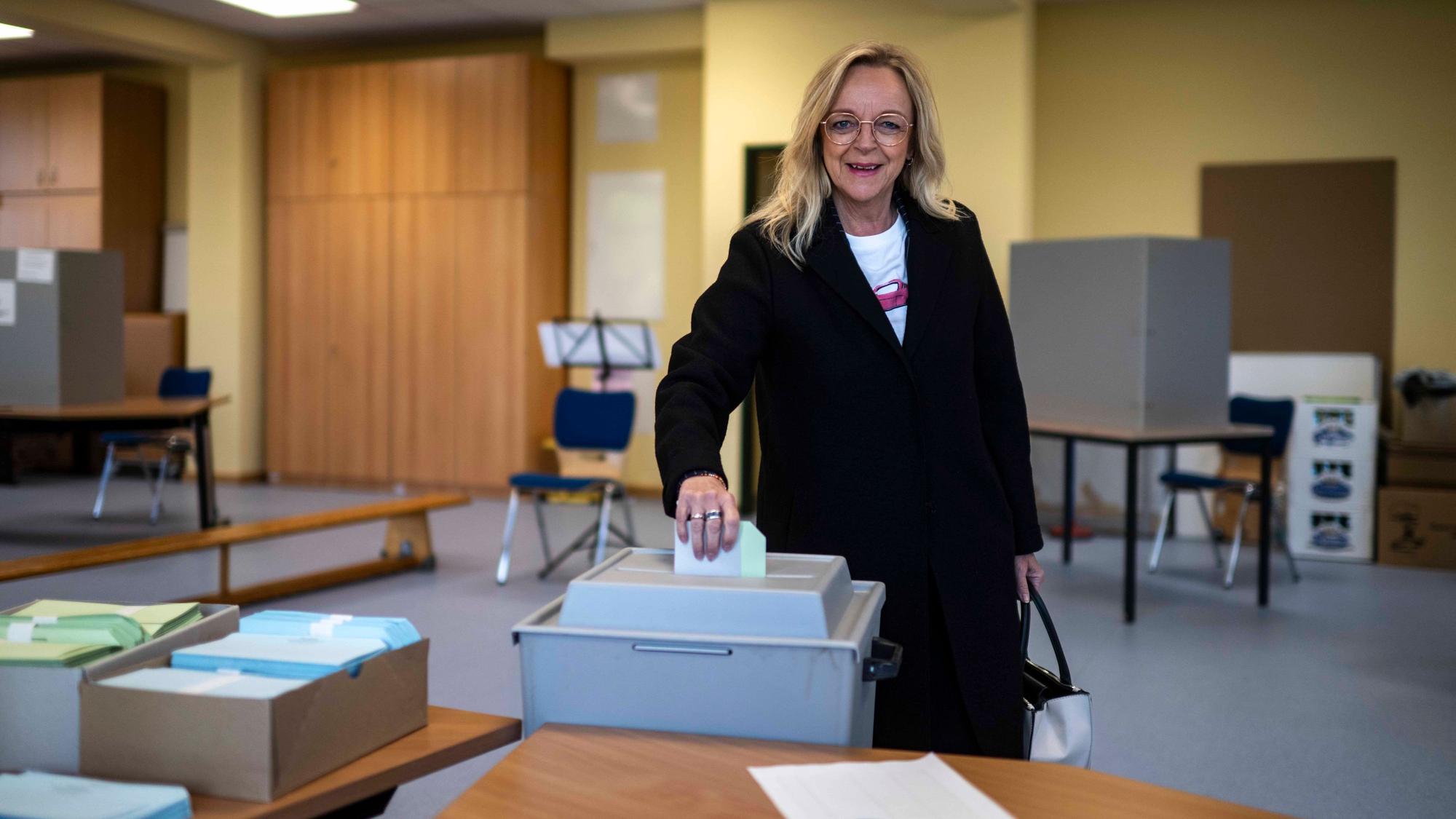 Sabine Preiser-Marian, die Landratskandidatin der CDU im Kreis Euskirchen, trägt einen schwarzen Mantel und gibt im Wahllokal in Bad Münstereifel-Arloff ihre Stimmzettel in eine graue Wahlurne.