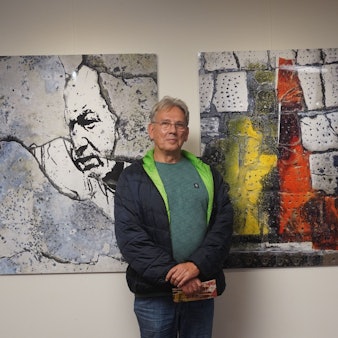 Zu sehen ist Wilhelm Goertz vor zwei seiner Werke.