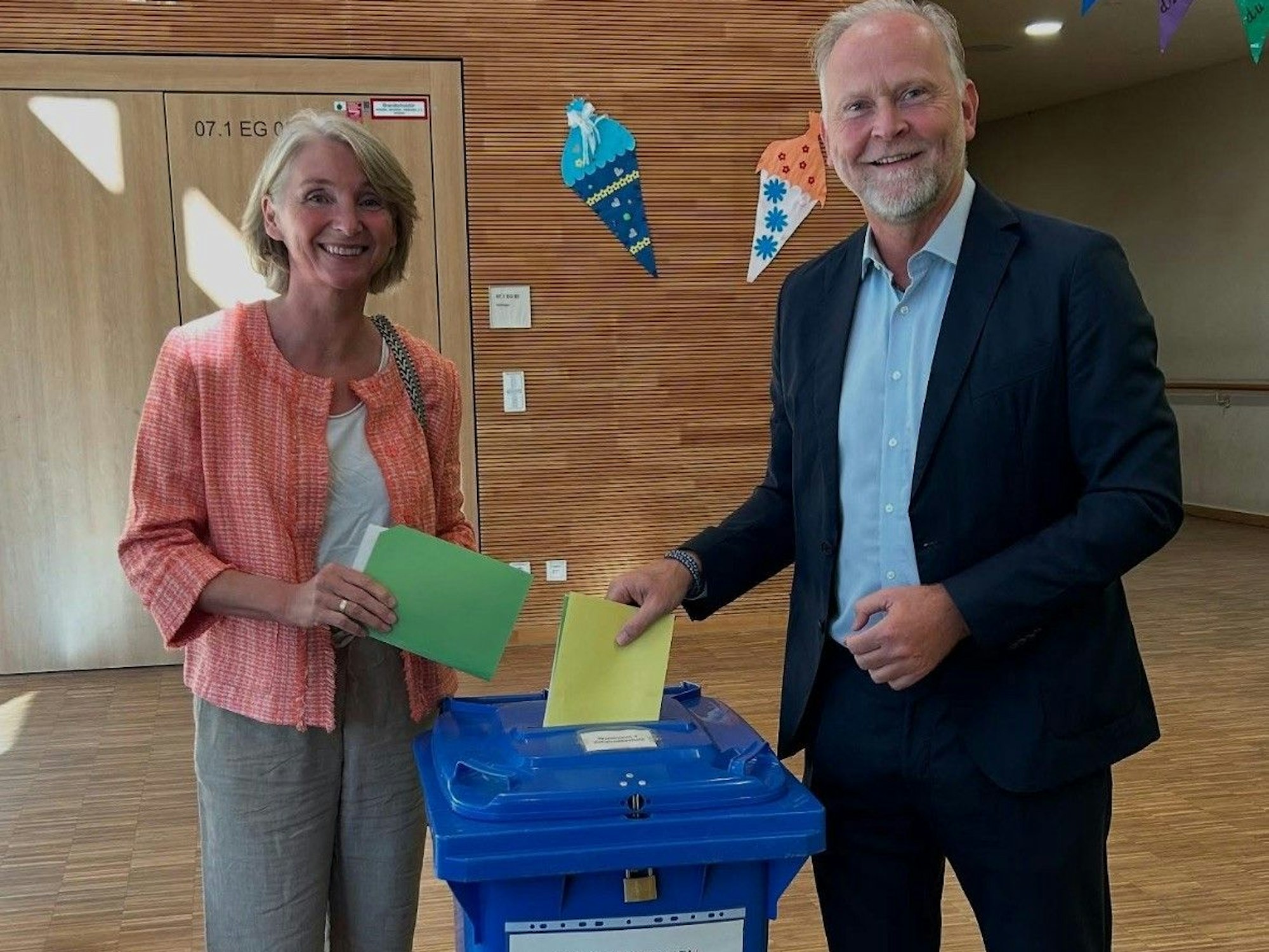 Auf dem Bild ist ein Ehepaar an einer Wahlurne zu sehen.