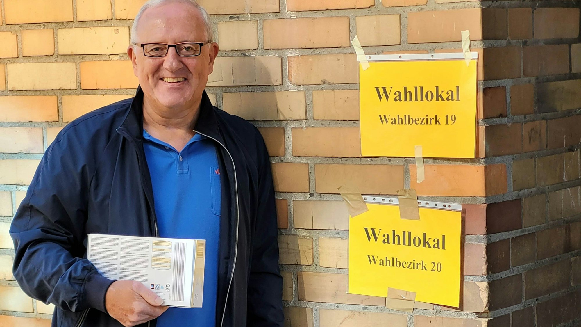 Auf dem Bild ist ein Mann vor einem Wahllokal zu sehen.
