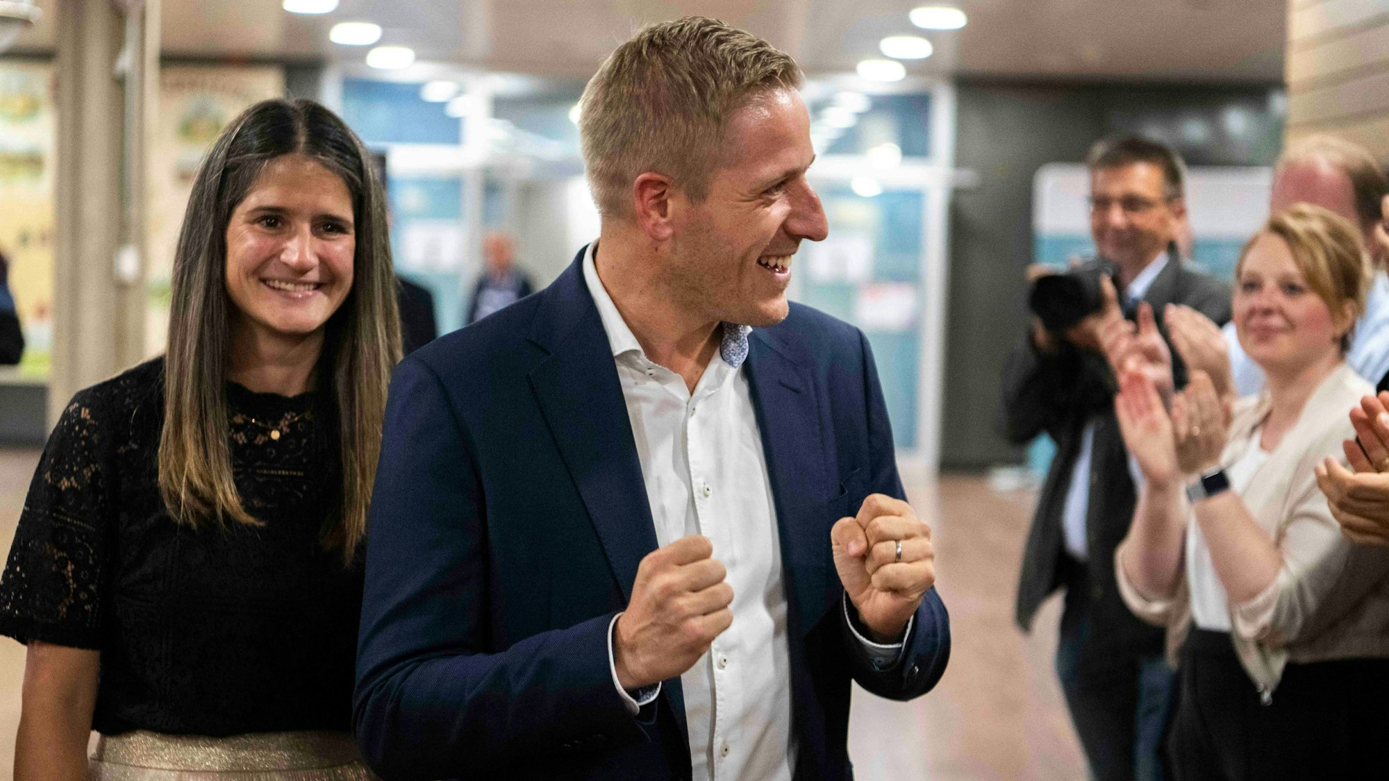 Das Bild zeigt Markus Ramers, wie er an einem Spalier vorbeigeht und sich über seinen Sieg freut.