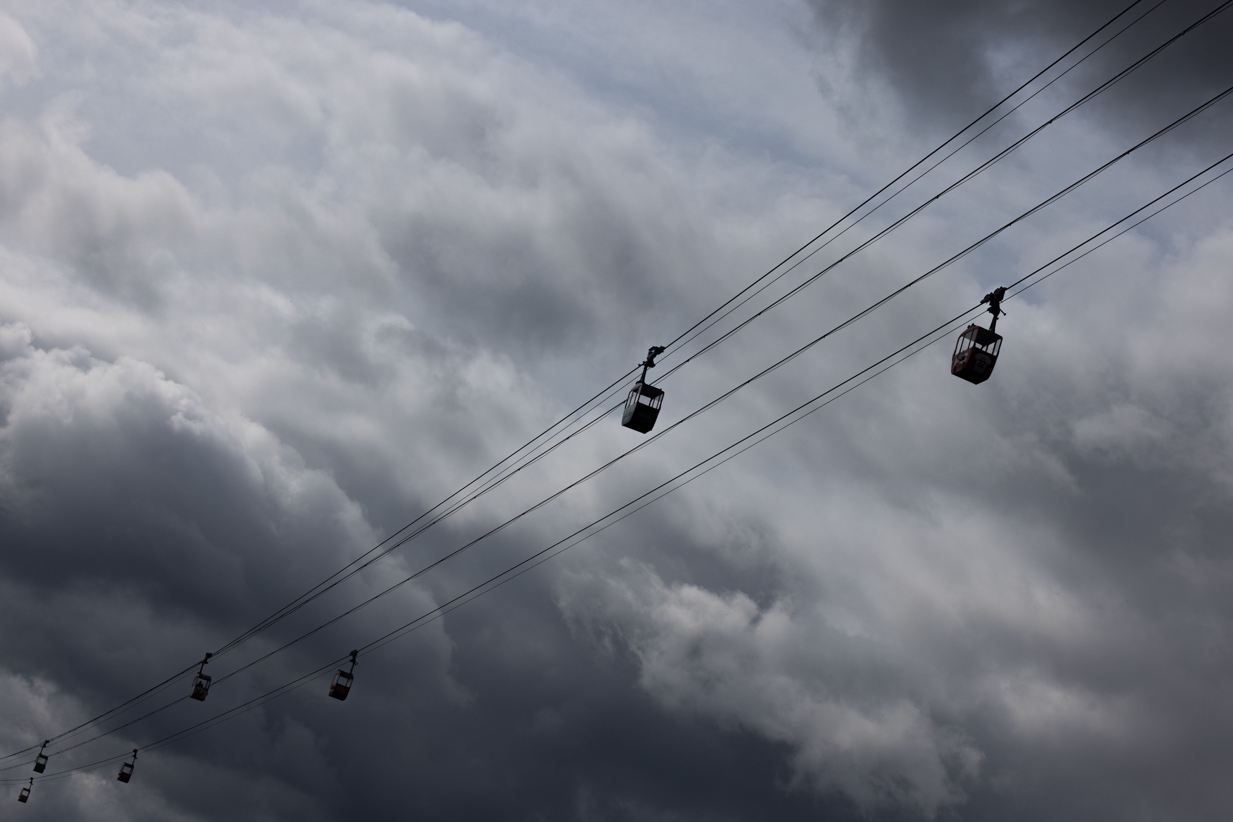 Die Seilbahn über den Rhein ist vor dunklen Wolken am Himmel zu sehen. Zu Pfingsten soll sich das Wetter drehen. (Archivbild)