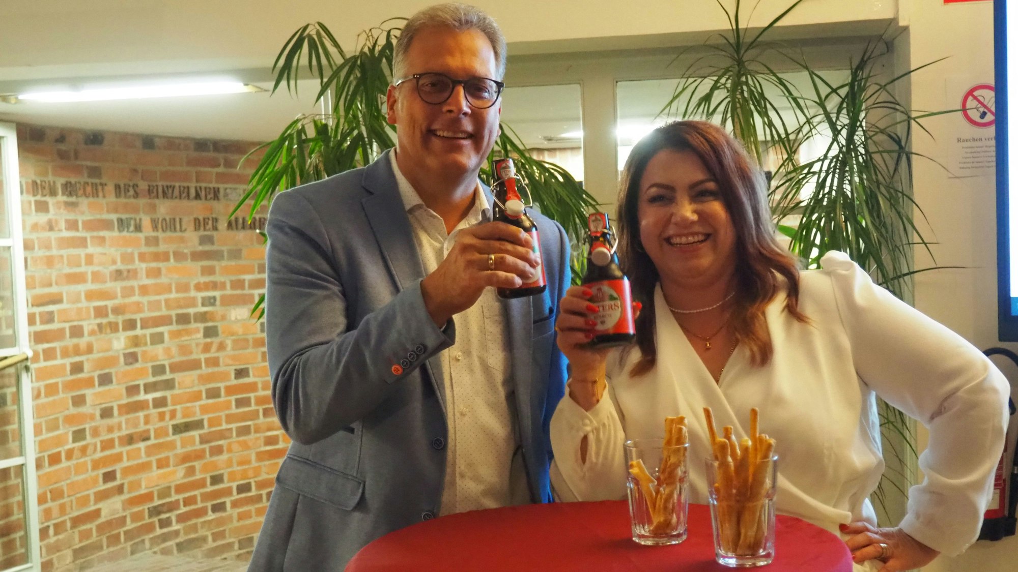 Nach der Kommunalwahl halten Zülpichs Bürgermeister Ulf Hürtgen und seine Gegenkandidatin Isabella Meurer jeder eine Flasche Bier in der Hand. Sie stoßen auf den fairen Wahlkampf an, den sie geführt haben.