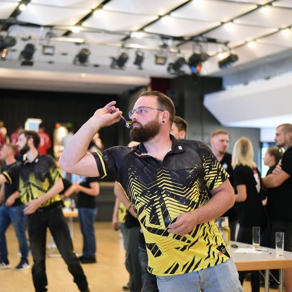 Ein Mann wirft einen Pfeil auf eine E-Dartscheibe.