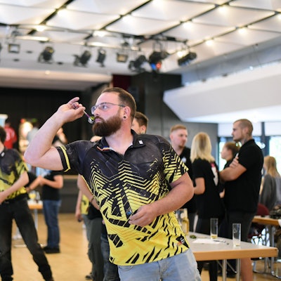Ein Mann wirft einen Pfeil auf eine E-Dartscheibe.