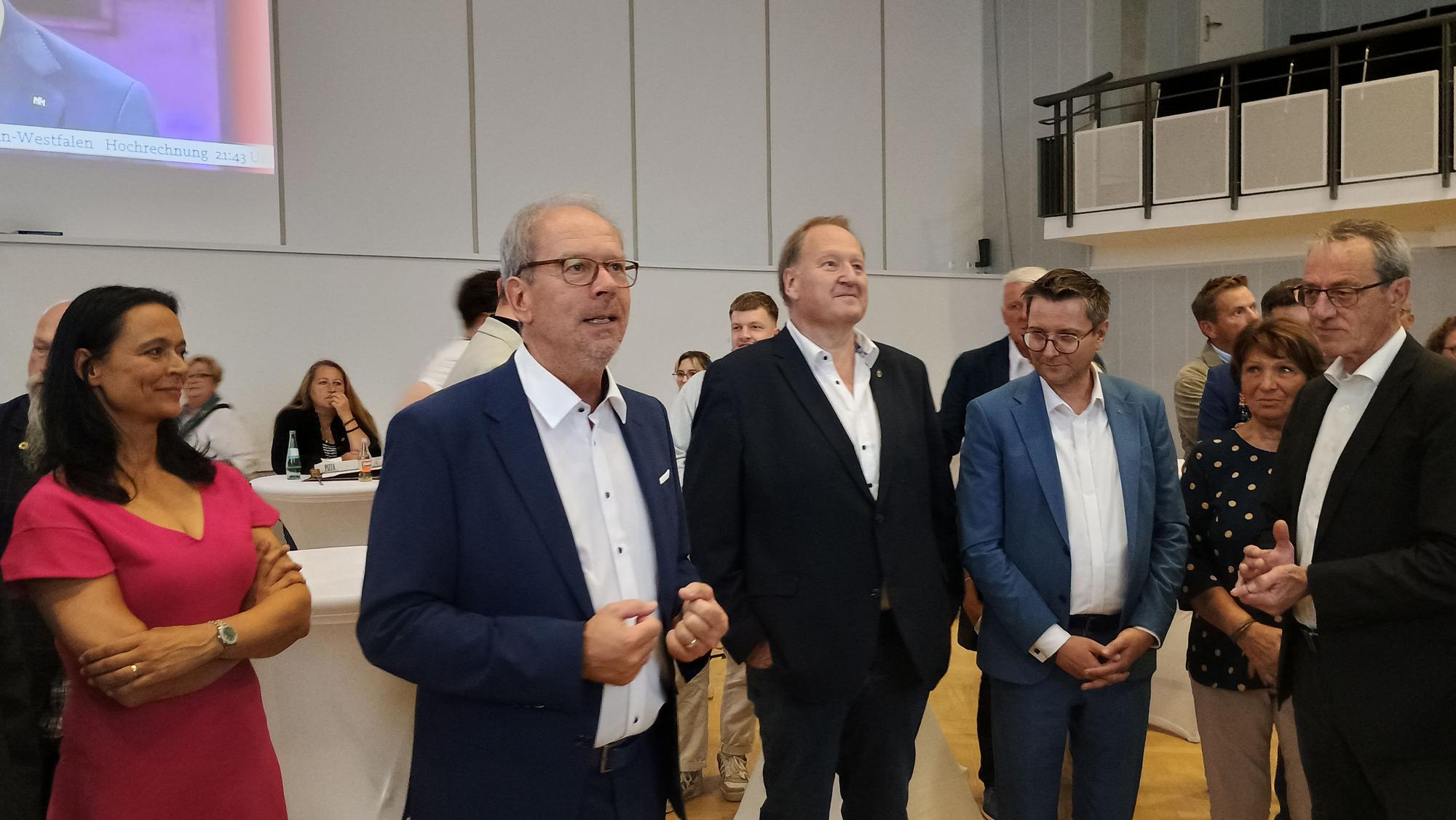 Zu sehen ist der Bürgermeister, der nach der Wahl eine kleine Ree hält, neben ihm stehen seine Frau sowie weitere Politiker.