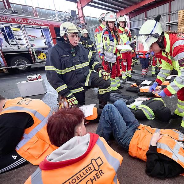 Jugendliche Darsteller, denen Verletzungen angeschminkt wurden, liegen auf dem Boden und werden von Sanitätern und Feuerwehrleuten versorgt.