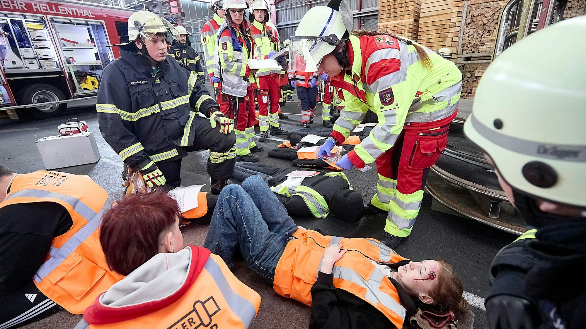 Jugendliche Darsteller, denen Verletzungen angeschminkt wurden, liegen auf dem Boden und werden von Sanitätern und Feuerwehrleuten versorgt.