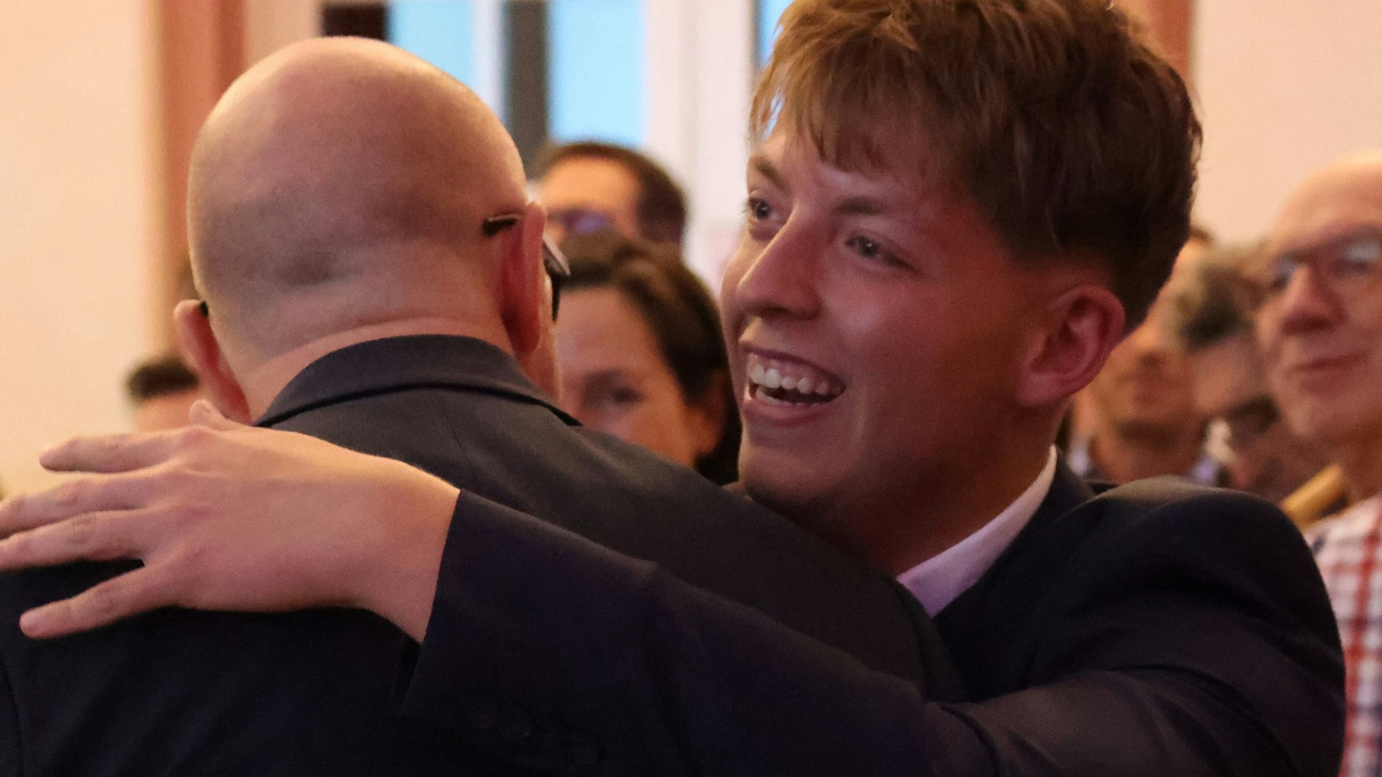 Jordan Blum hat bei der Kommunalwahl in Schleiden ein Direktmandat gewonnen. Zur Gratulation nimmt ihn Bürgermeister Ingo Pfennings, der von hinten zu sehen ist, zur Gratulation in den Arm.