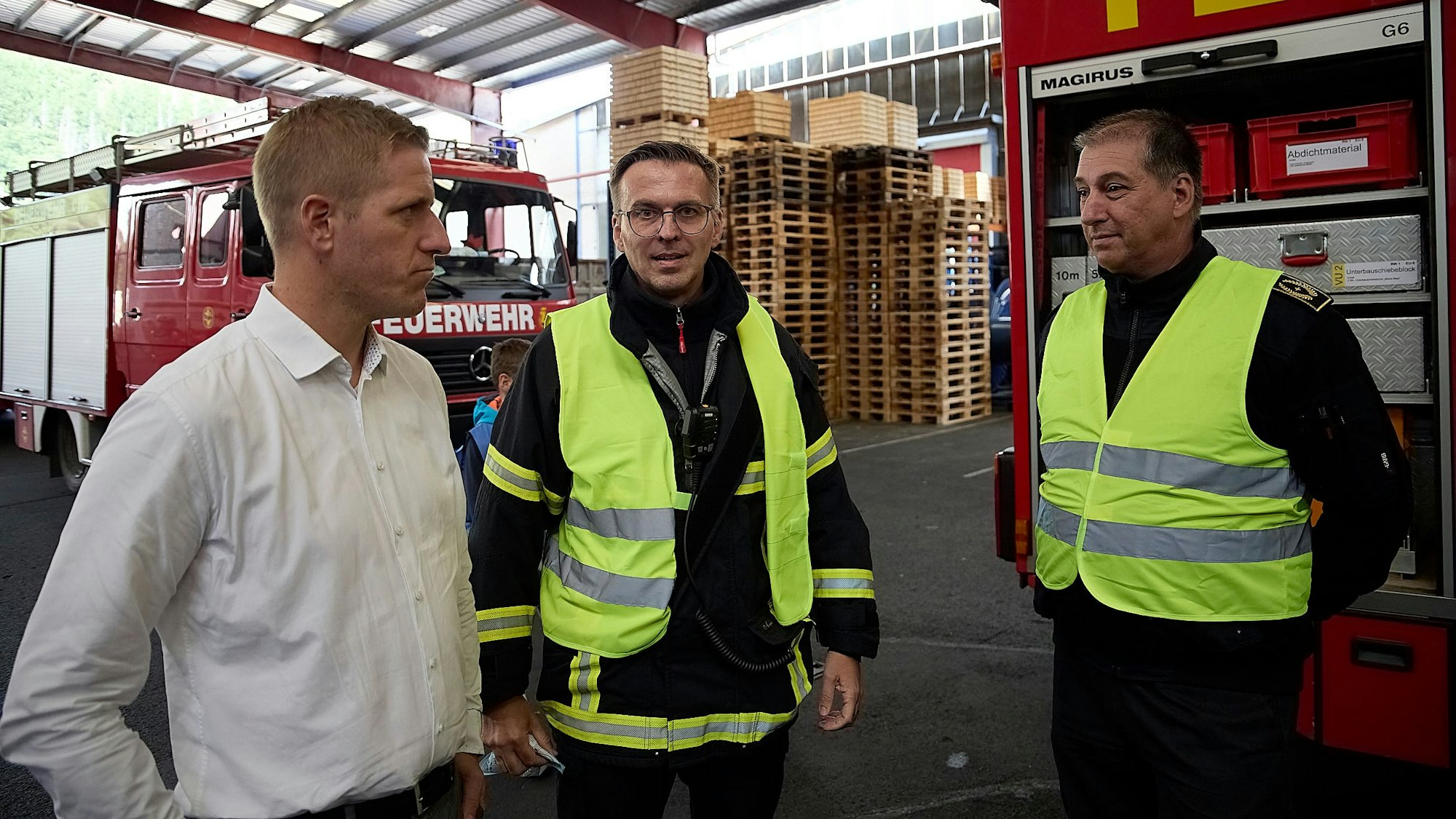 Die drei Genannten in der Werkhalle der Firma Schoeller, im Hintergrund zwei Feuerwehrfahrzeuge.