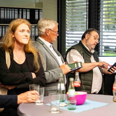 Das Bild zeigt Politiker, die teilweise auf ihr Handy schauen.