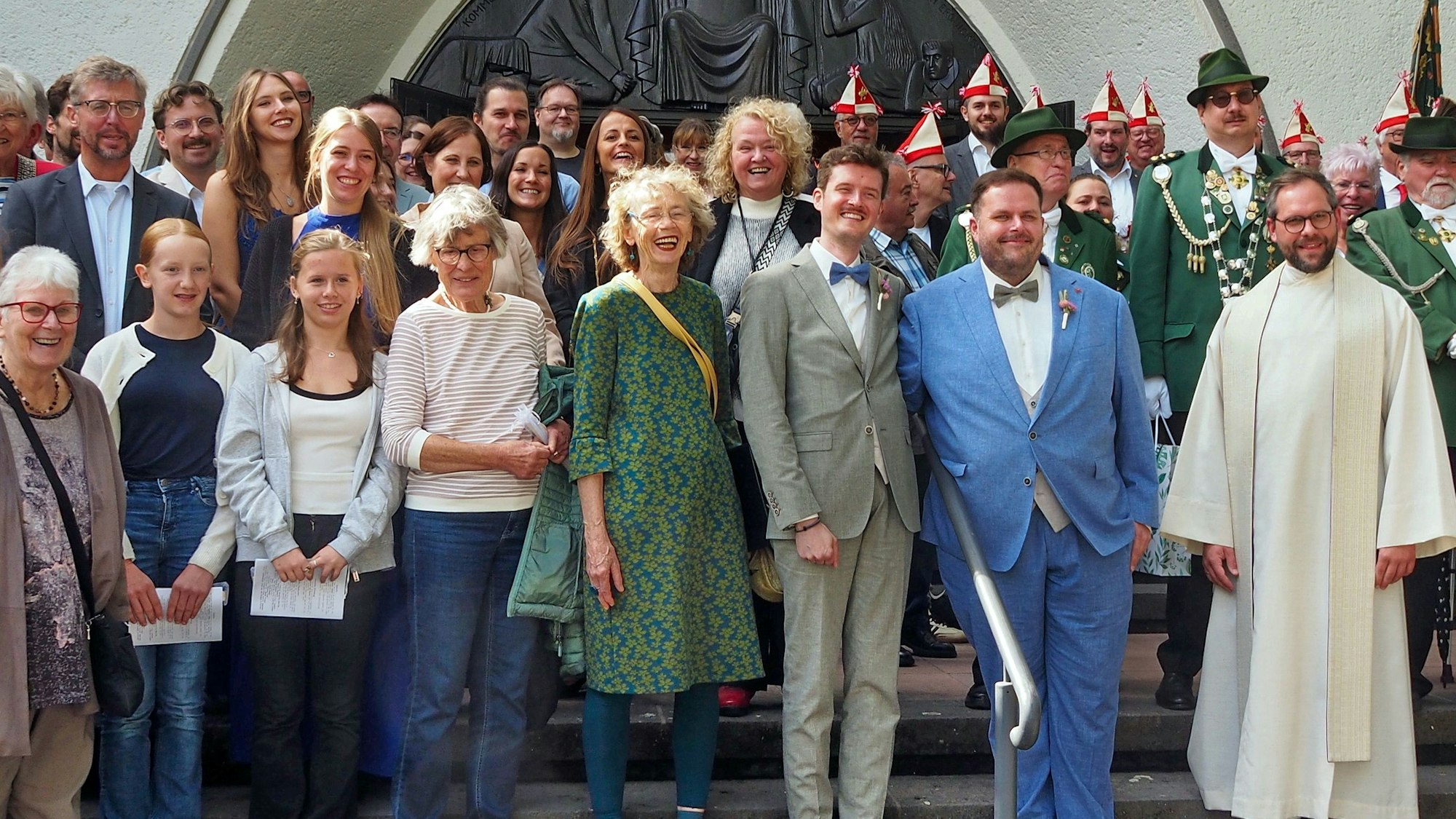 Viele Menschen stehen auf den Stufen vor einer Kirche.