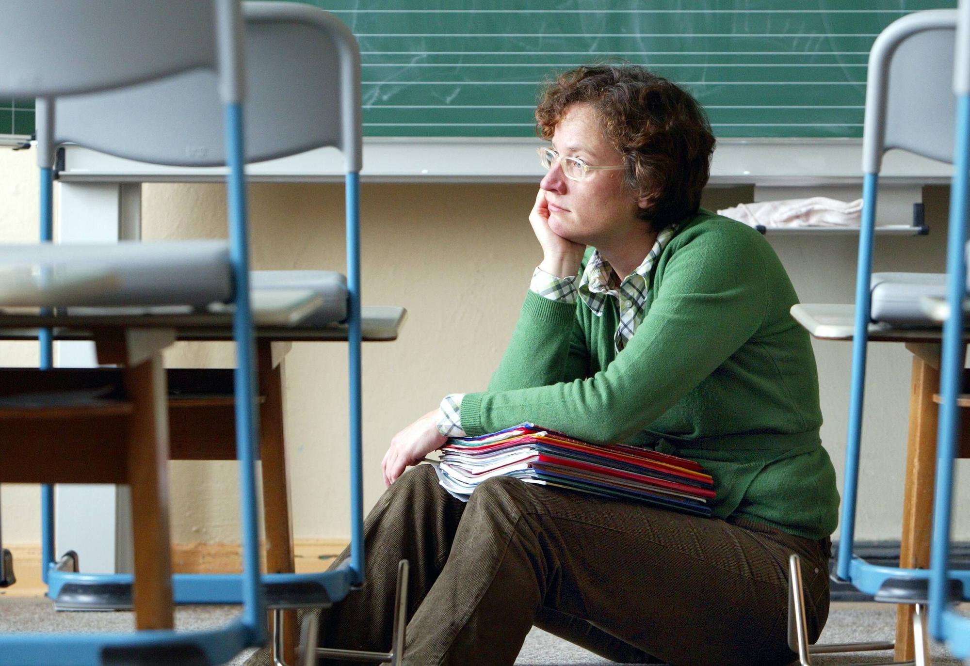 Lehrerin sitzt alleine in einem Klassenraum