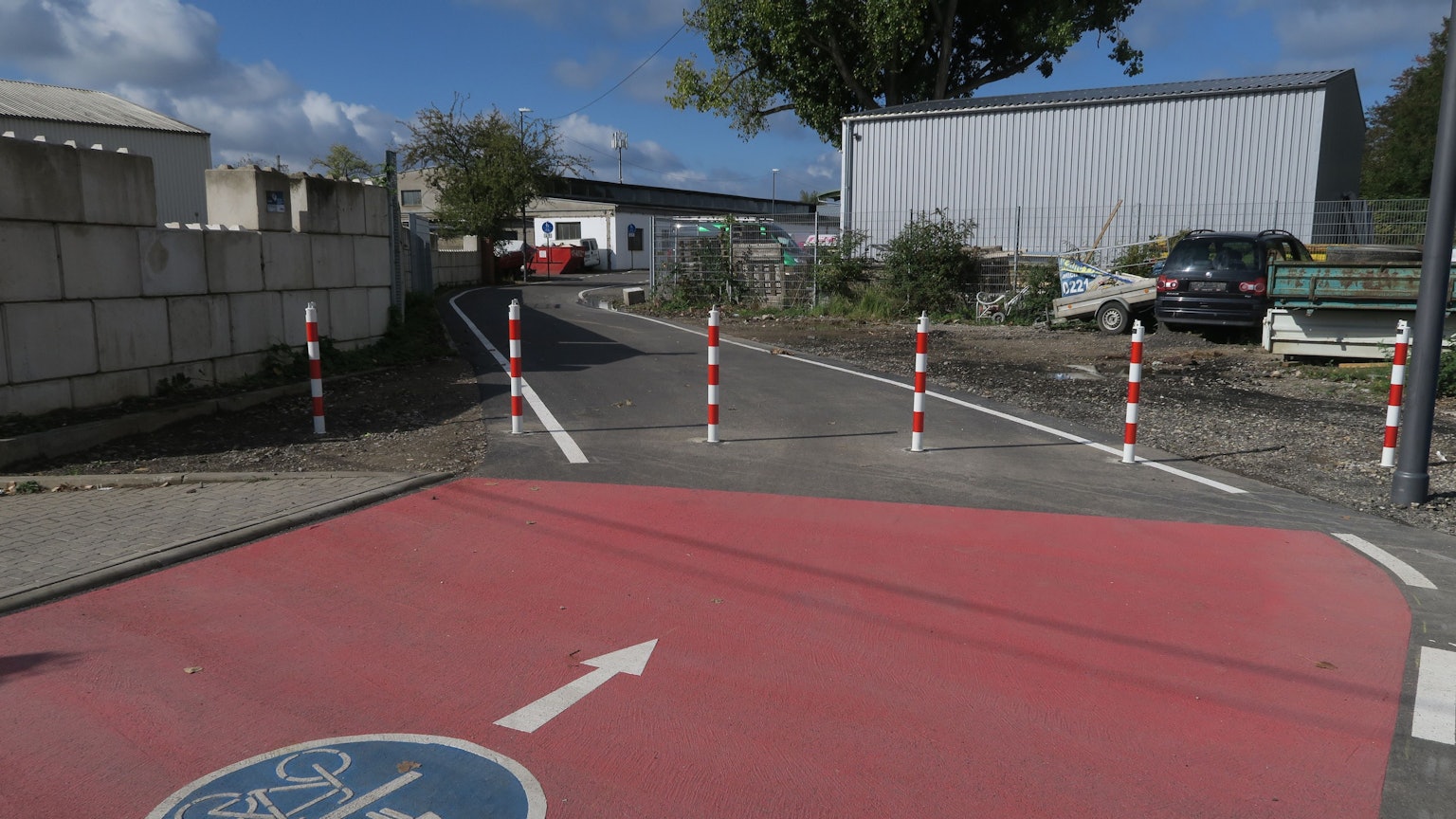 Ein Rad- und Fußwegmarkierung ist frisch aufgebracht auf einer schmalen asphaltierten Straße.