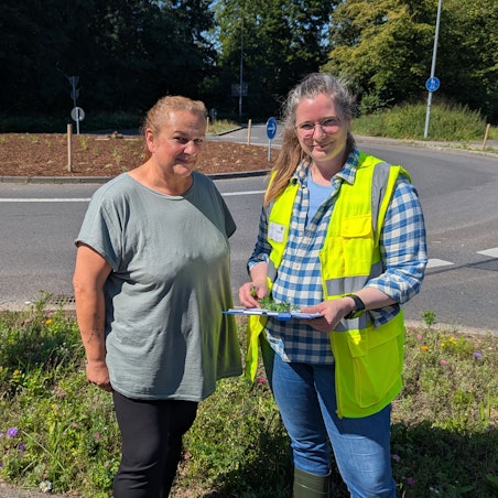 Das Foto zeigt zwei Frauen mit einem Klemmbrett vor dem Kreisverkehr an der Theresienhöhe am Hürth-Park.