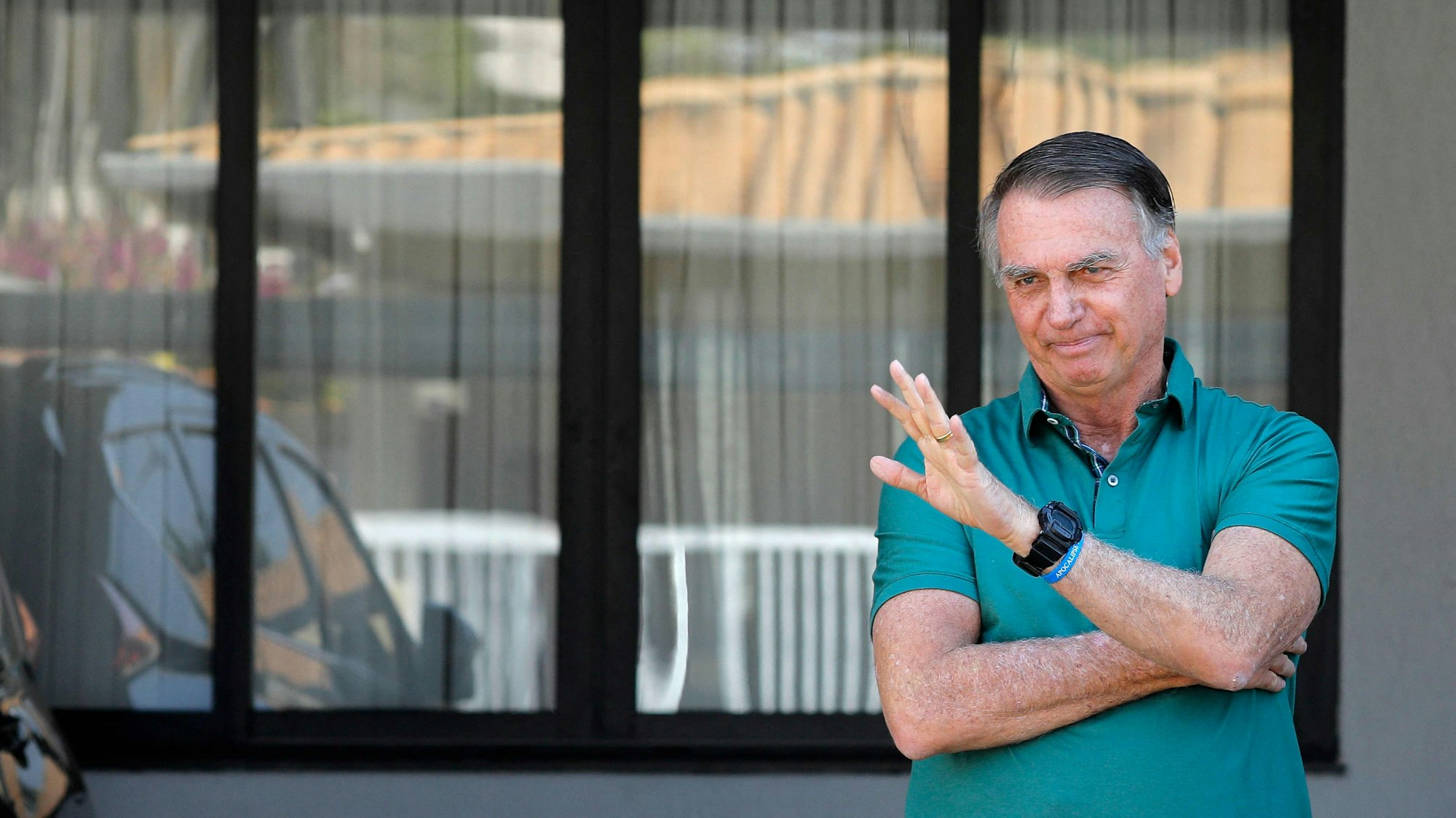 (FILES) Former Brazilian President Jair Bolsonaro waves at his residence in Brasilia on September 11, 2025. Brazil's former president Jair Bolsonaro was rushed to hospital with a police guard on September 16, 2025, after falling ill while under house arrest, his son Flavio said. (Photo by Sergio Lima / AFP)