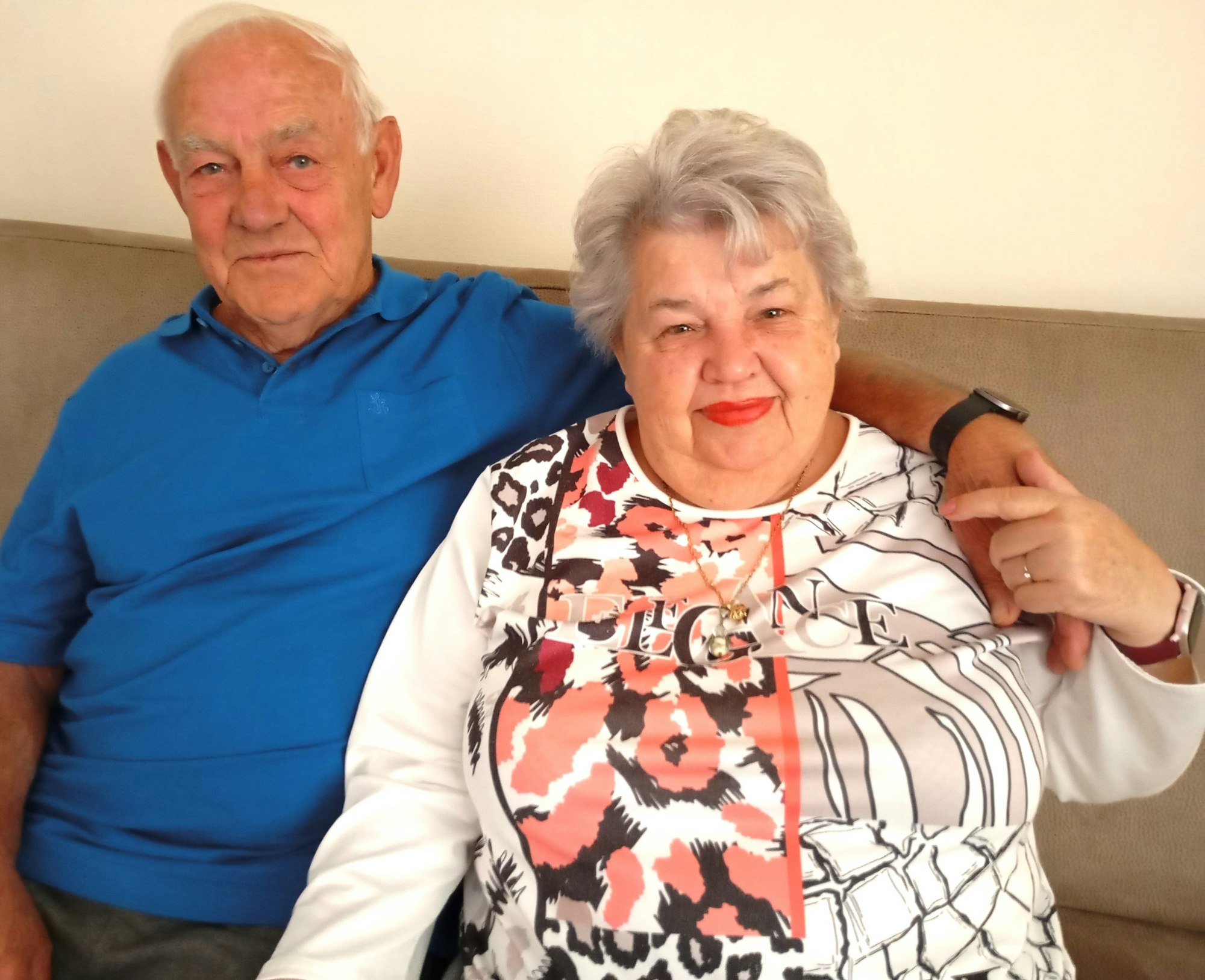 Ein älteres Ehepaar sitzt auf einem Sofa nebeneinander.