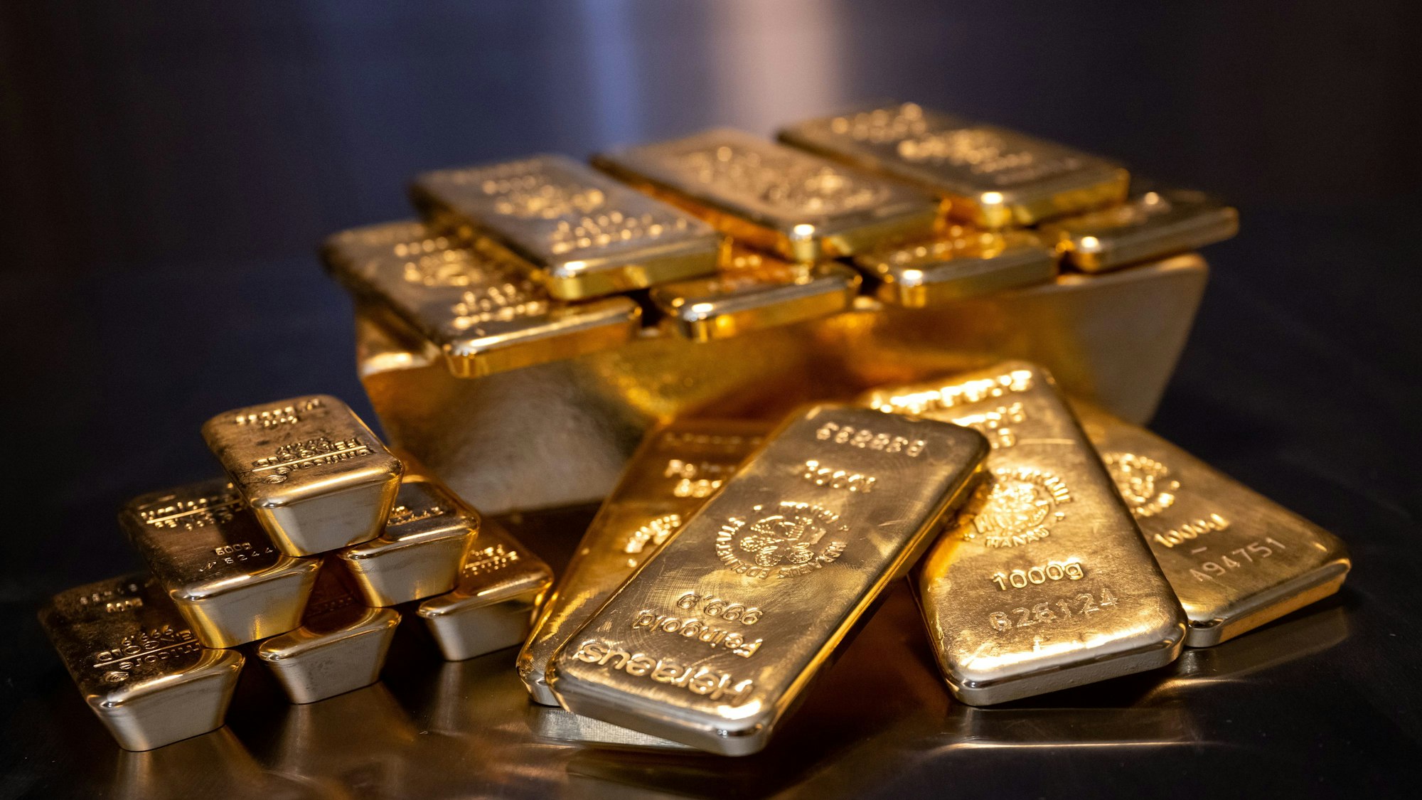 Goldbarren unterschiedlicher Größe liegen auf einem Tisch.