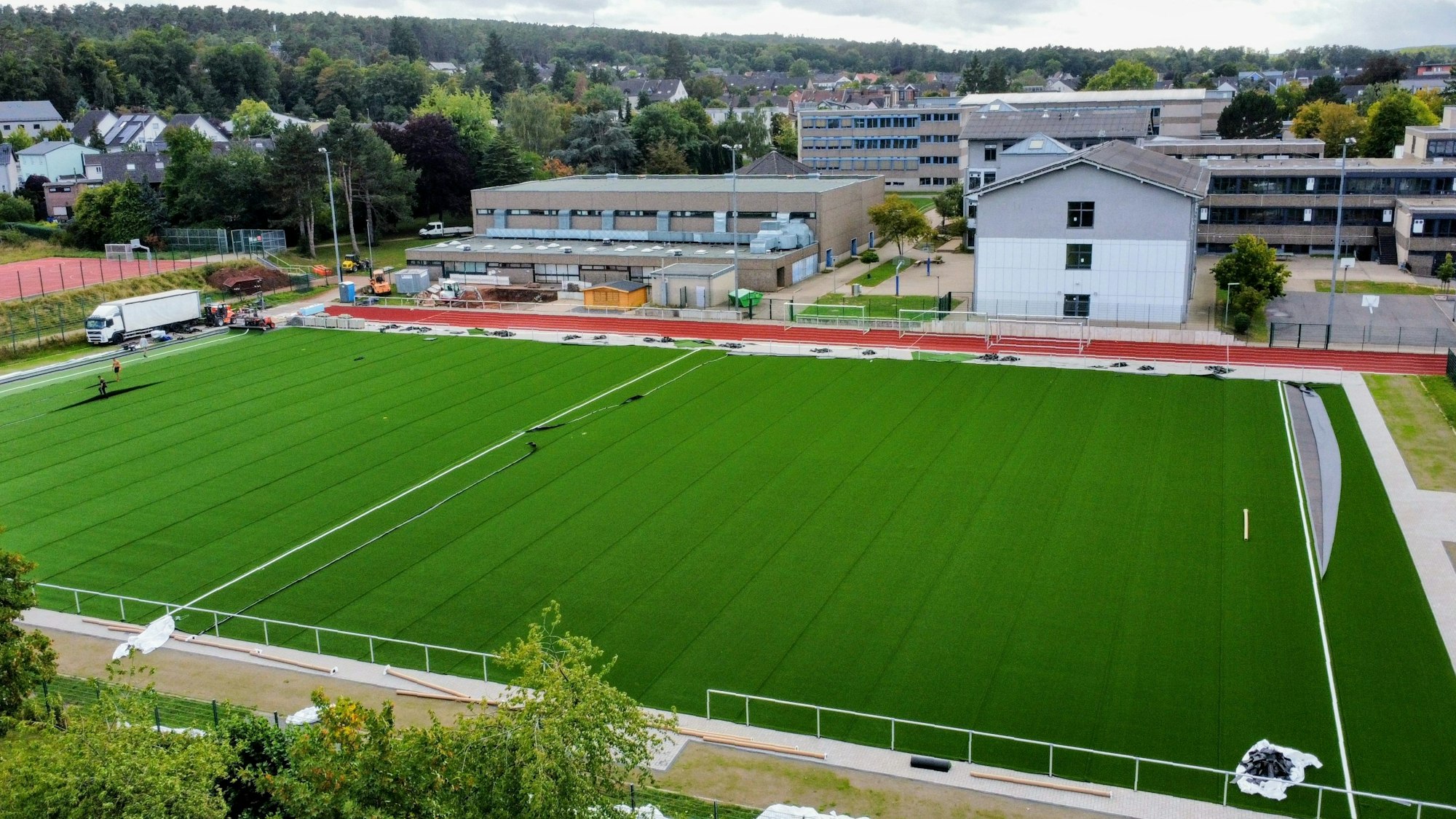 Luftbild (Drohnenaufnahme) des neuen Kunstrasenplatzes am Mechernicher Schulzentrum. Im Hintergrund sind Gesamtschule und Gymnasium zu sehen.