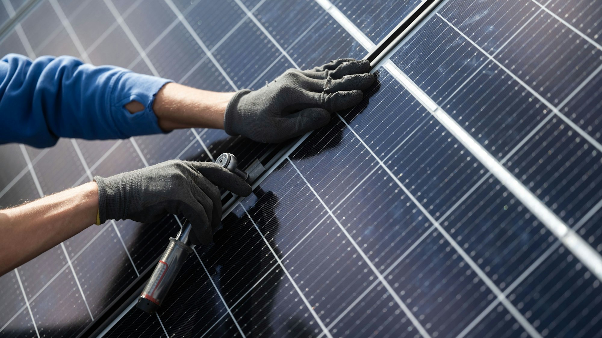 Ein Mann montiert Photovoltaikmodule auf dem Dach eines Wohnhauses.